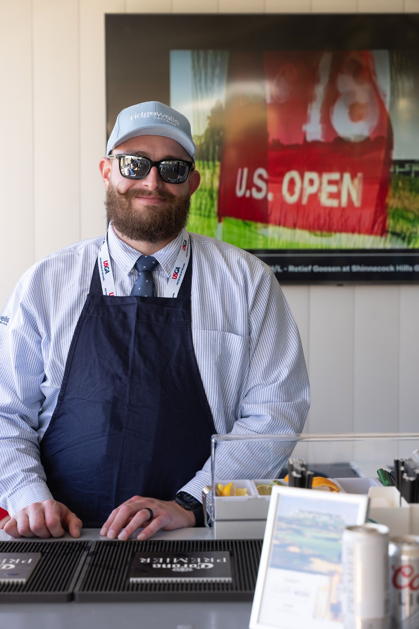 Corporate event photography of a bartender smiling inside the 1895 Club at the U.S. Open Golf Championship in the Hamptons, New York.