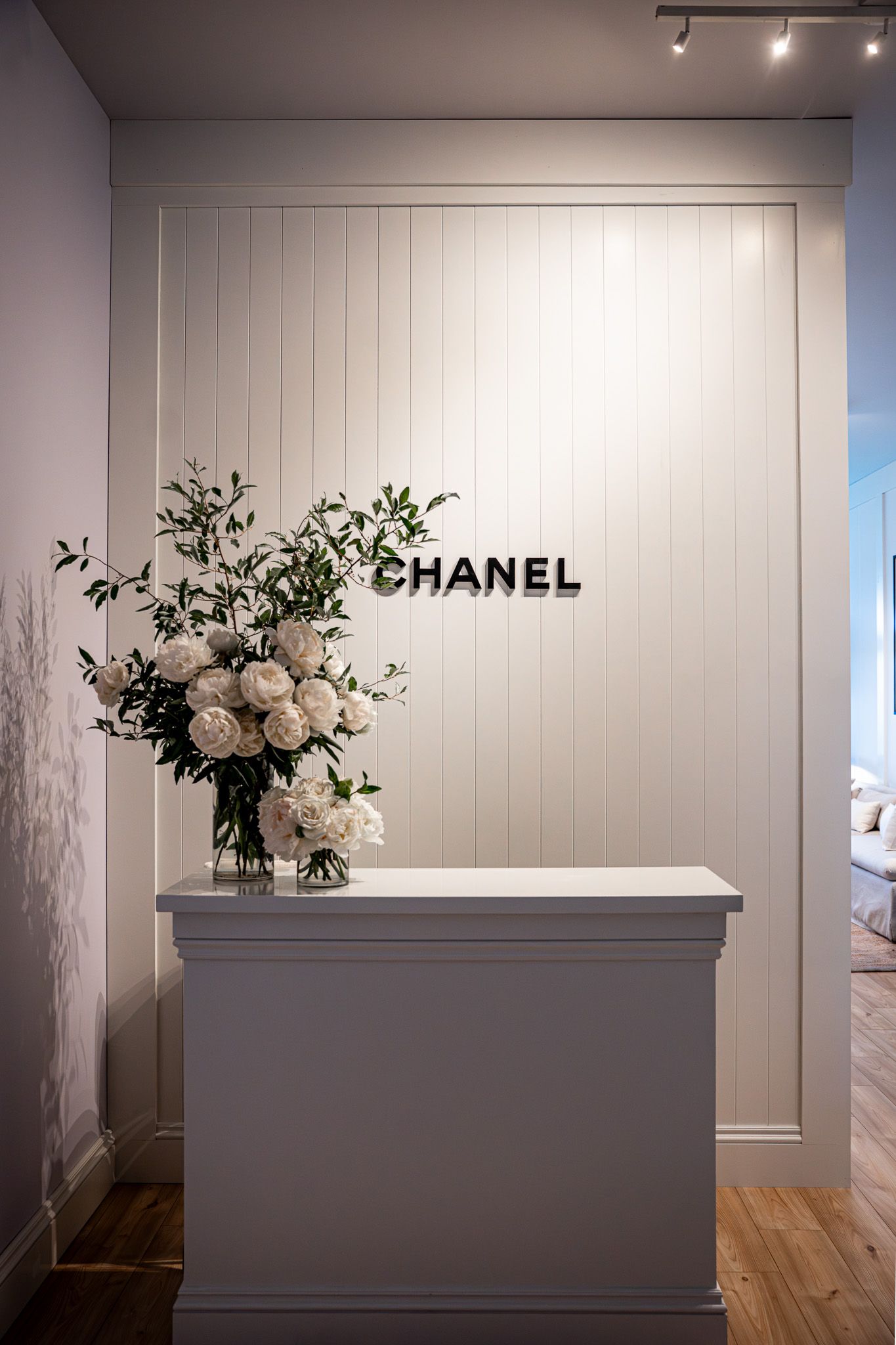 Corporate event photography of a company suite at the U.S. Open Golf Championship in the Hamptons, NY featuring a white wall & Chanel logo
