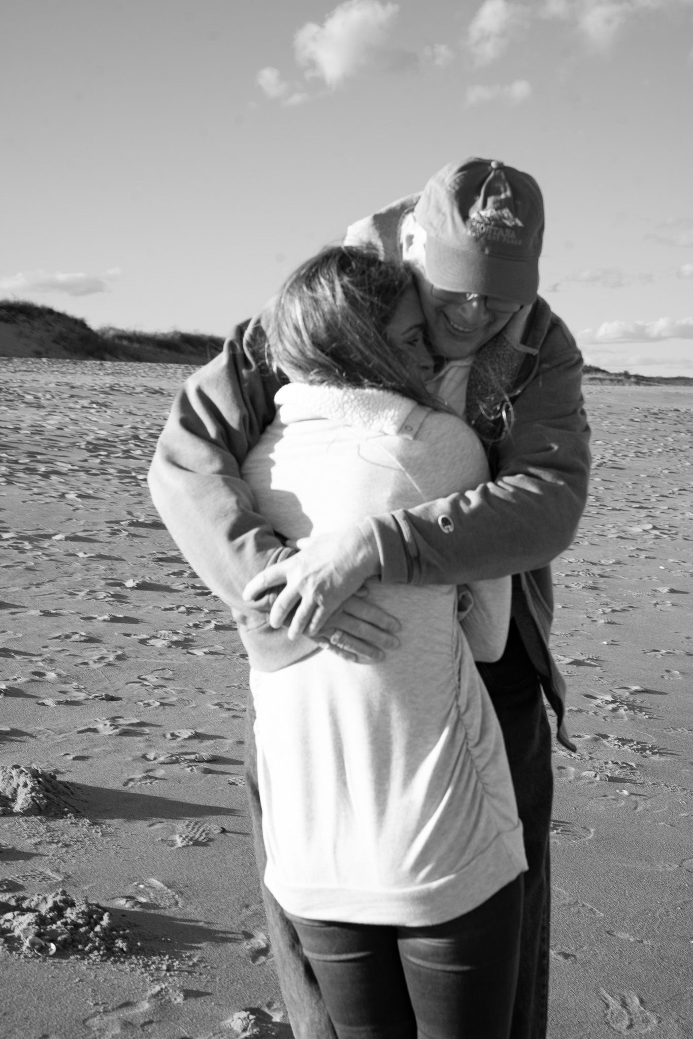 Family portrait of an adult woman being embraced by her father on the beach at Plum Island near Newburyport, Massachusetts