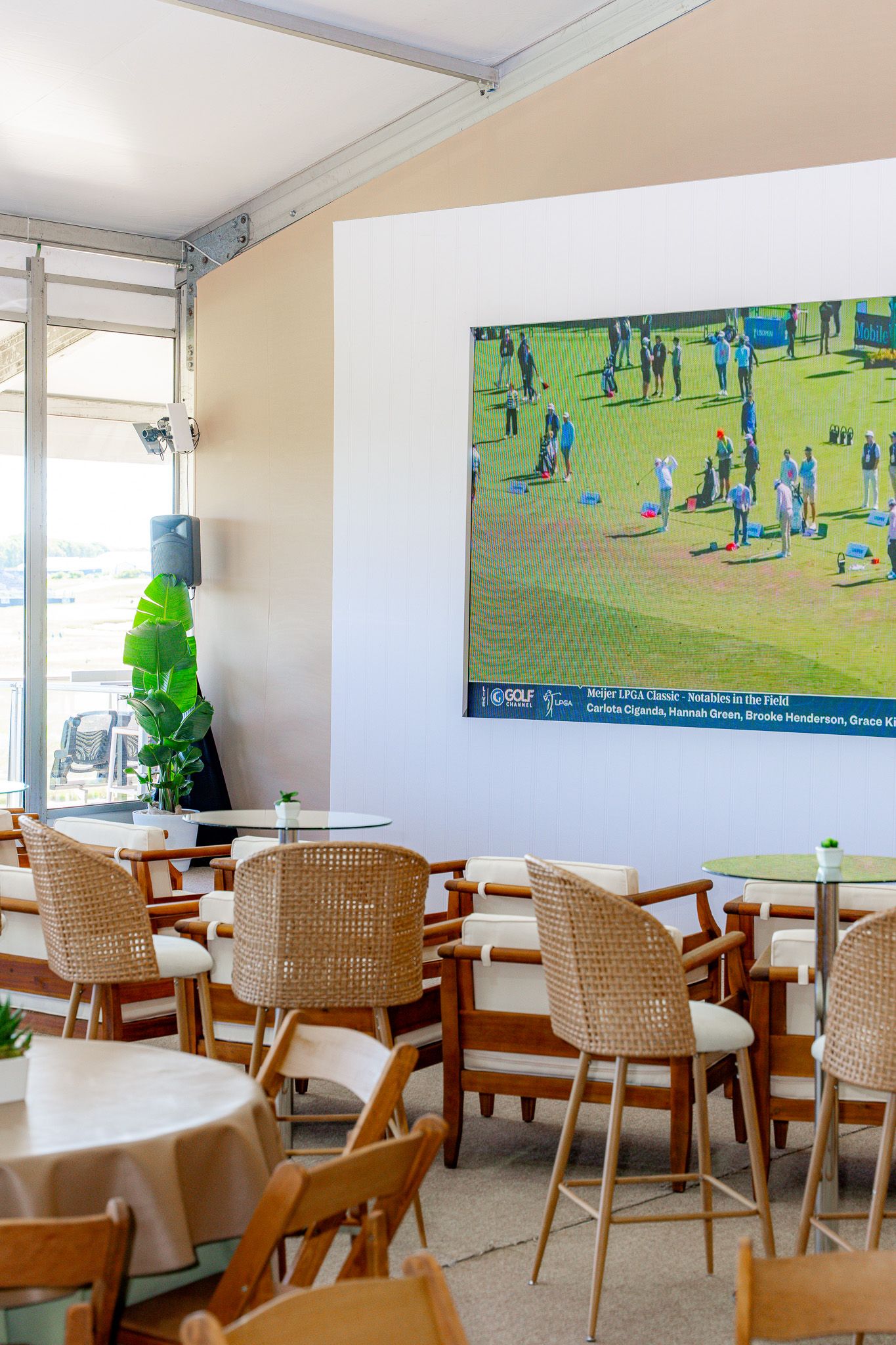 Corporate event photography of a company suite at the U.S. Open Golf Championship in the Hamptons, NY featuring small guest tables and a TV