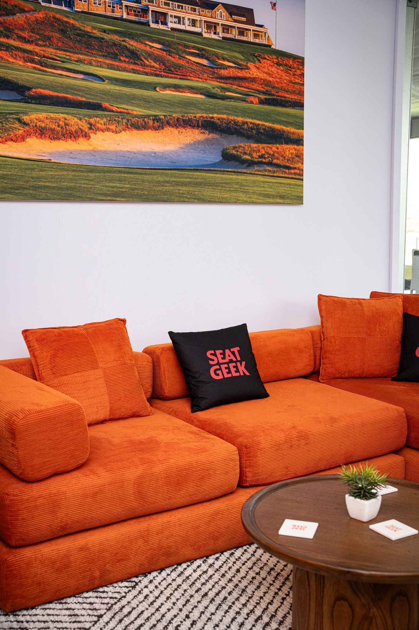 Corporate event photography of a company suite at the U.S. Open Golf Championship in the Hamptons, NY featuring a  bright orange couch