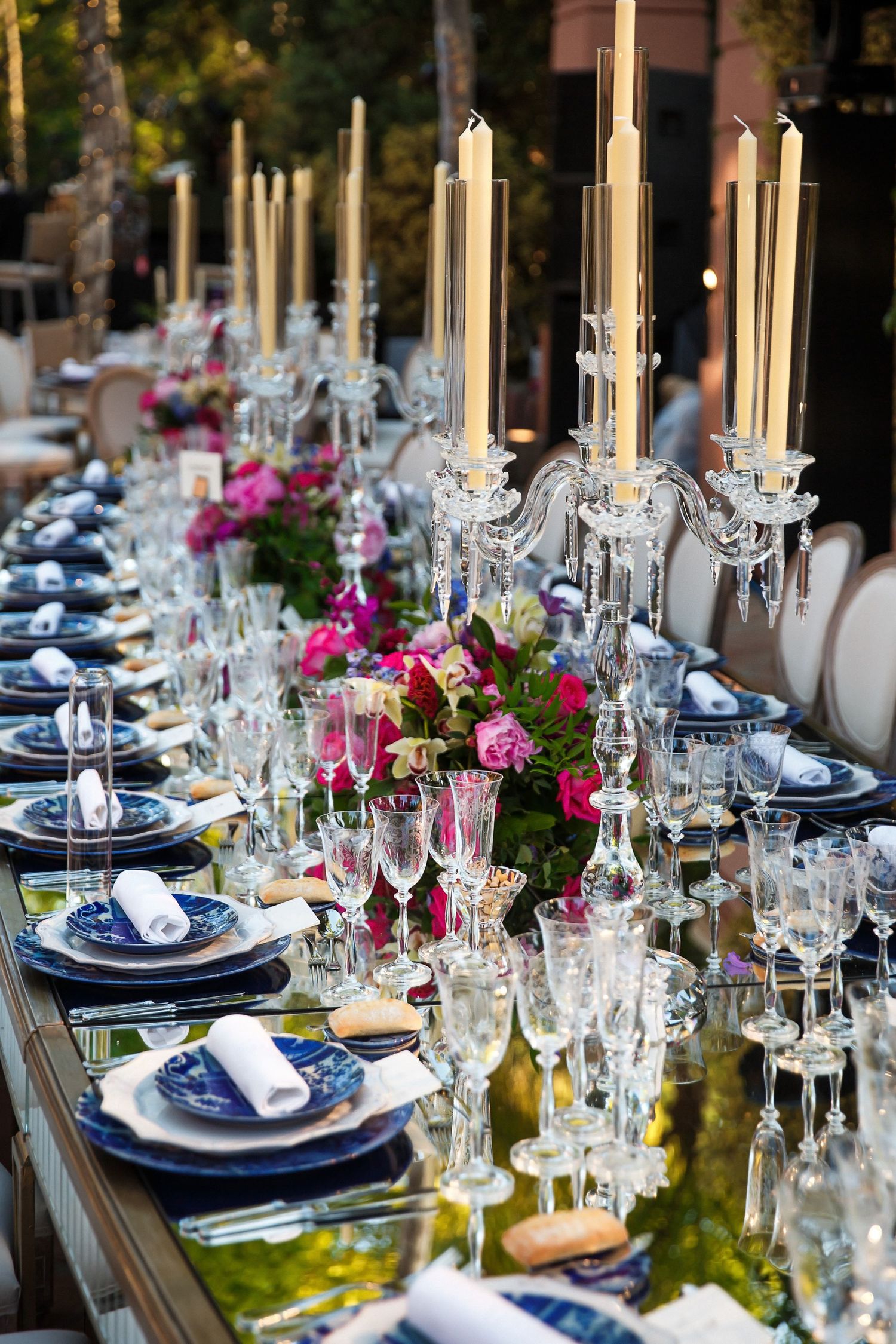 Dozens of tall lit tapered candles on a custom made gold table with fragrant rose centerpieces at a luxury wedding in Boston, Massachusetts