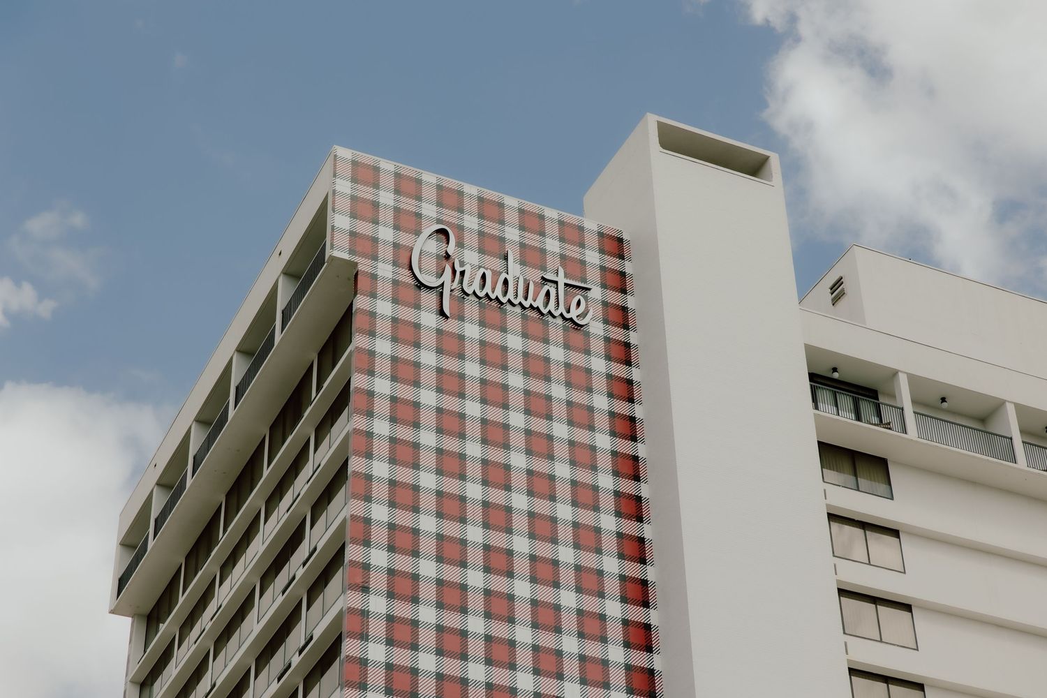 Photo of the graduate hotel in Fayetteville Arkansas from the outside with red plaid pattern on a bright sunny wedding day.
