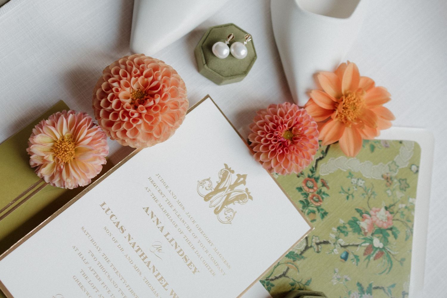 Wedding detail photo showcasing invitation, shoes, jewelry, and colorful florals.