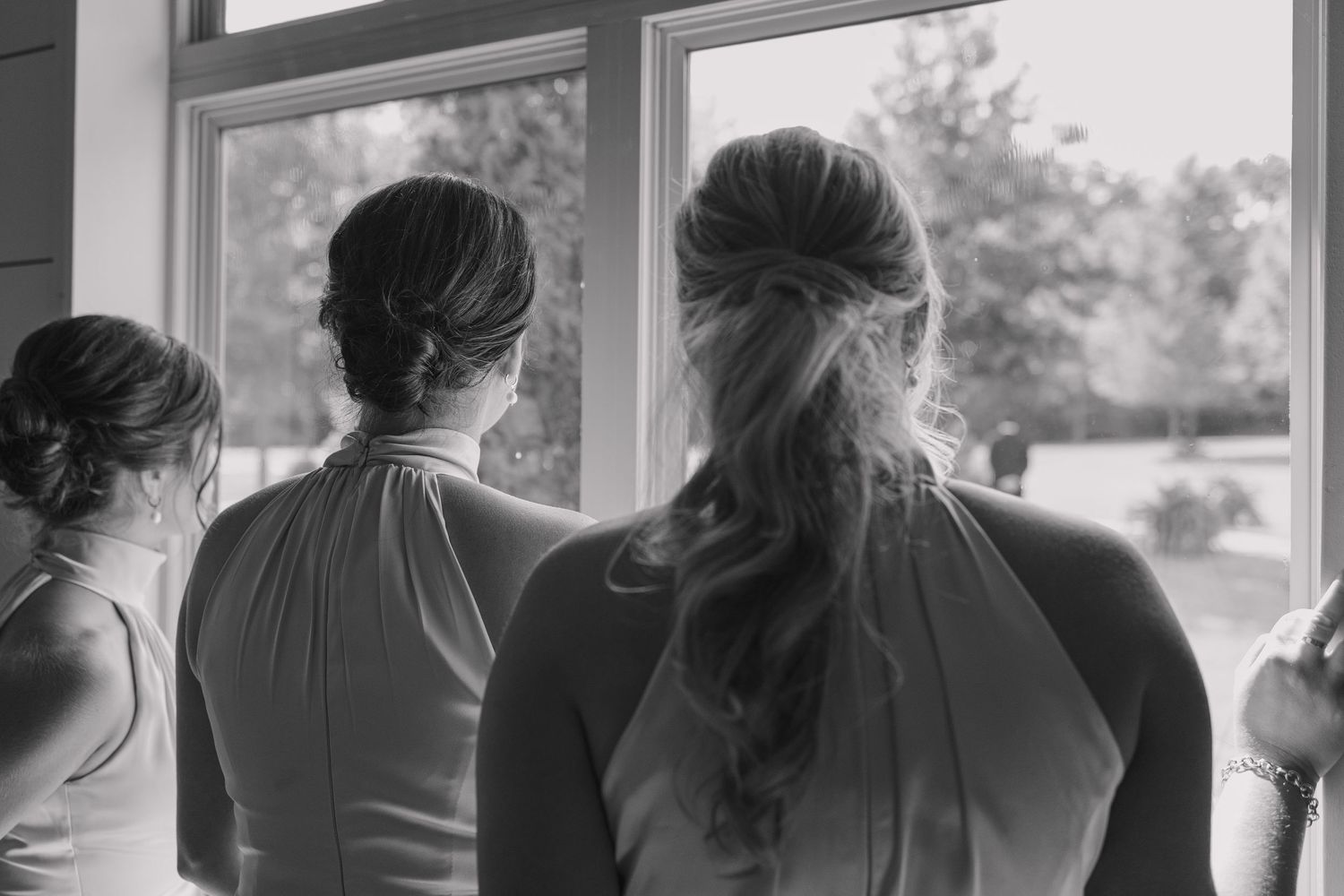 Documentary style moment of bridesmaids looking out of a window during wedding.