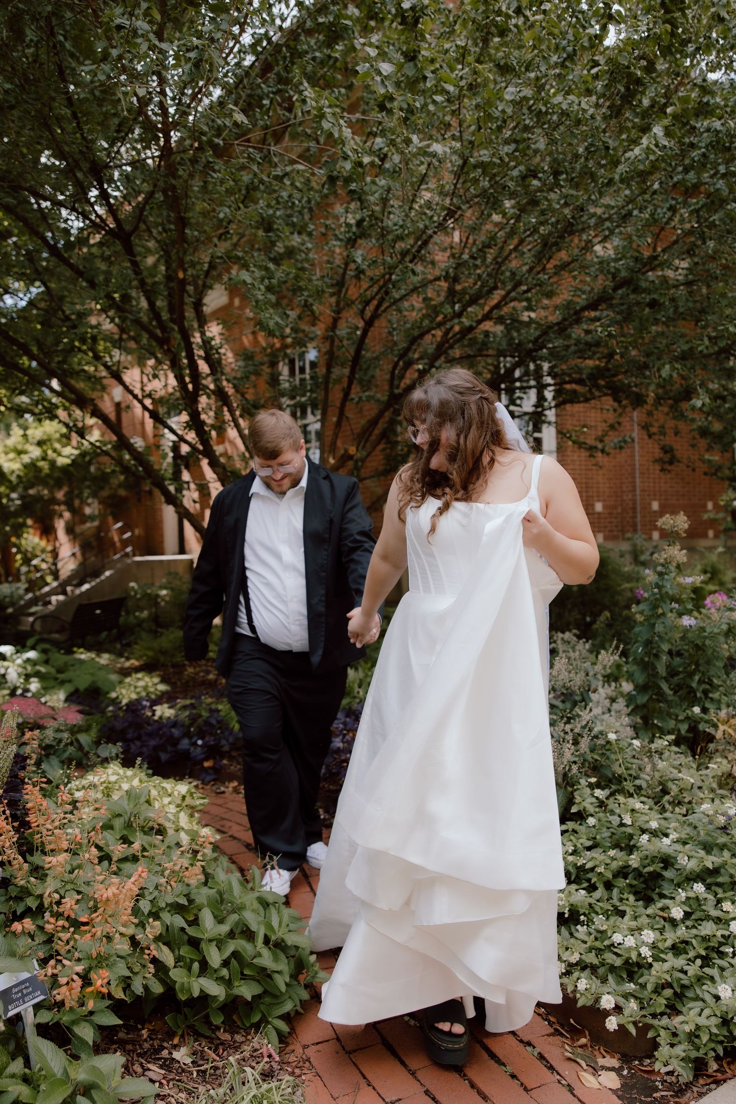 Elopement couple in a candid moment walking through the gardens of the downtown Fayetteville, Arkansas square area.