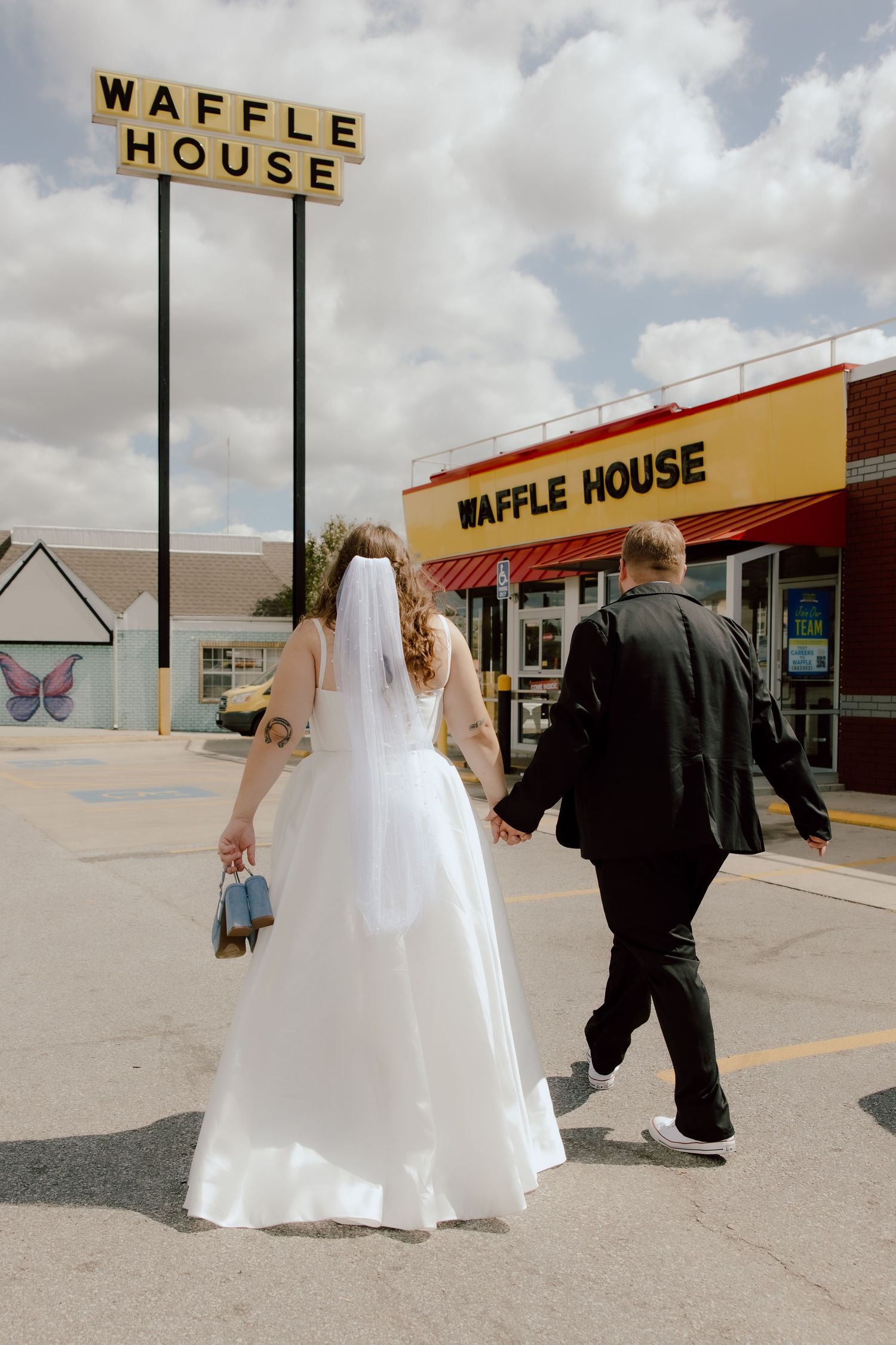 Bride and groom walking into Waffle House in Fayetteville, Arkansas on a sunny summer day after their elopement style wedding day.