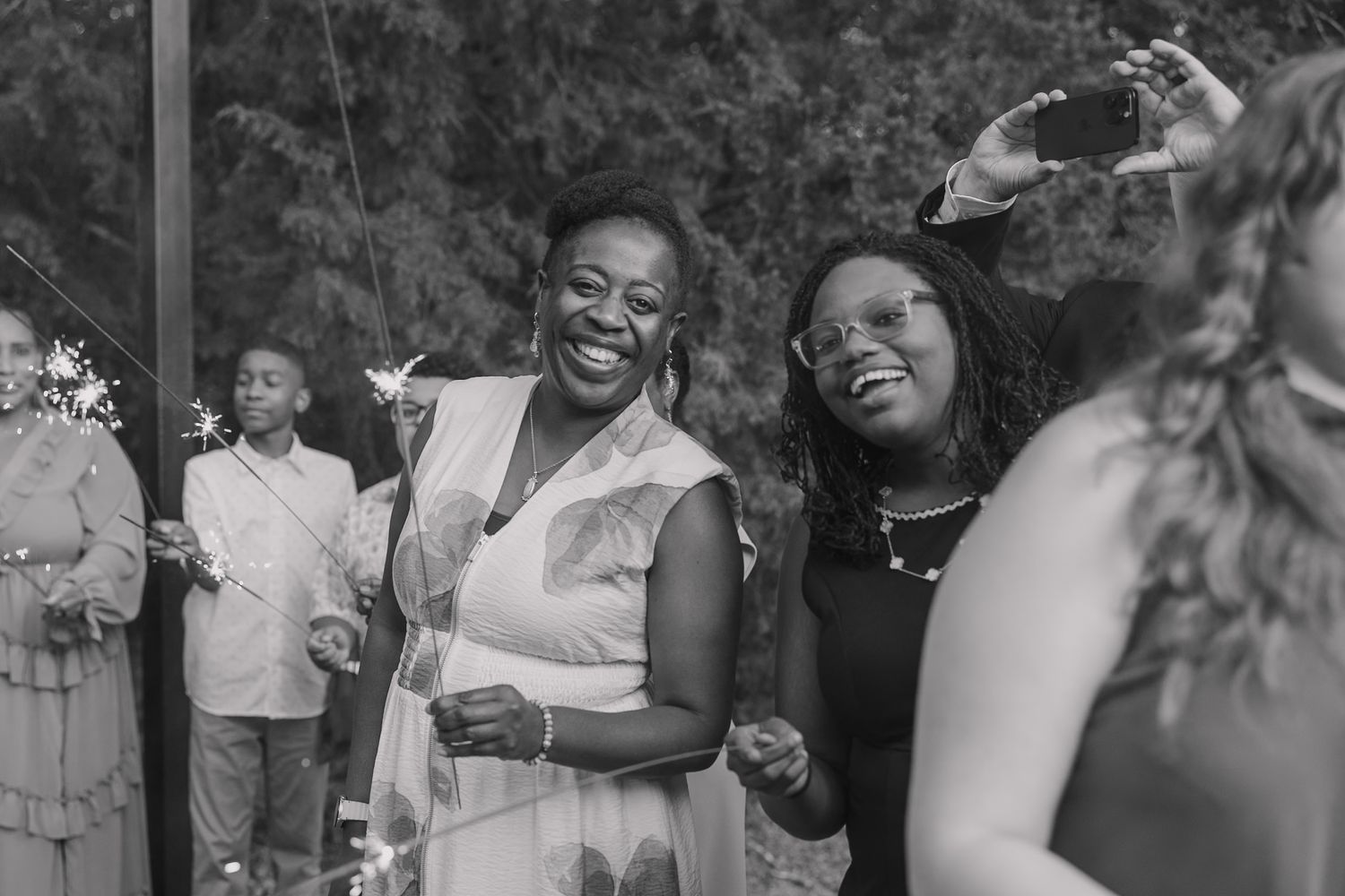 Wedding guests smiling with sparklers before the bride and groom exit their wedding.