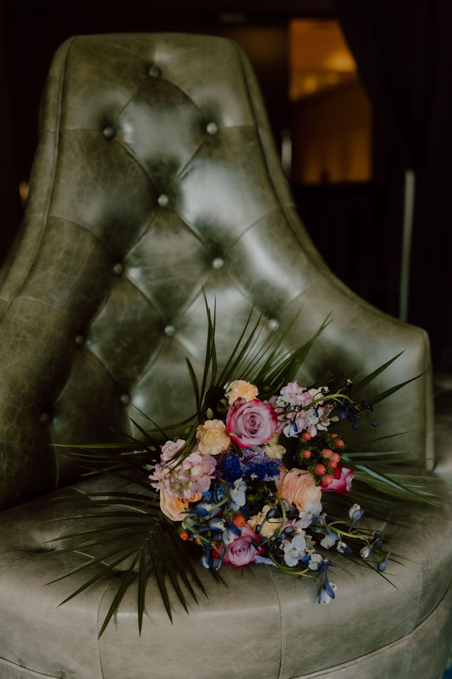 Green leather chair at the graduate hotel with the brides colorful bright bouquet sitting on it.