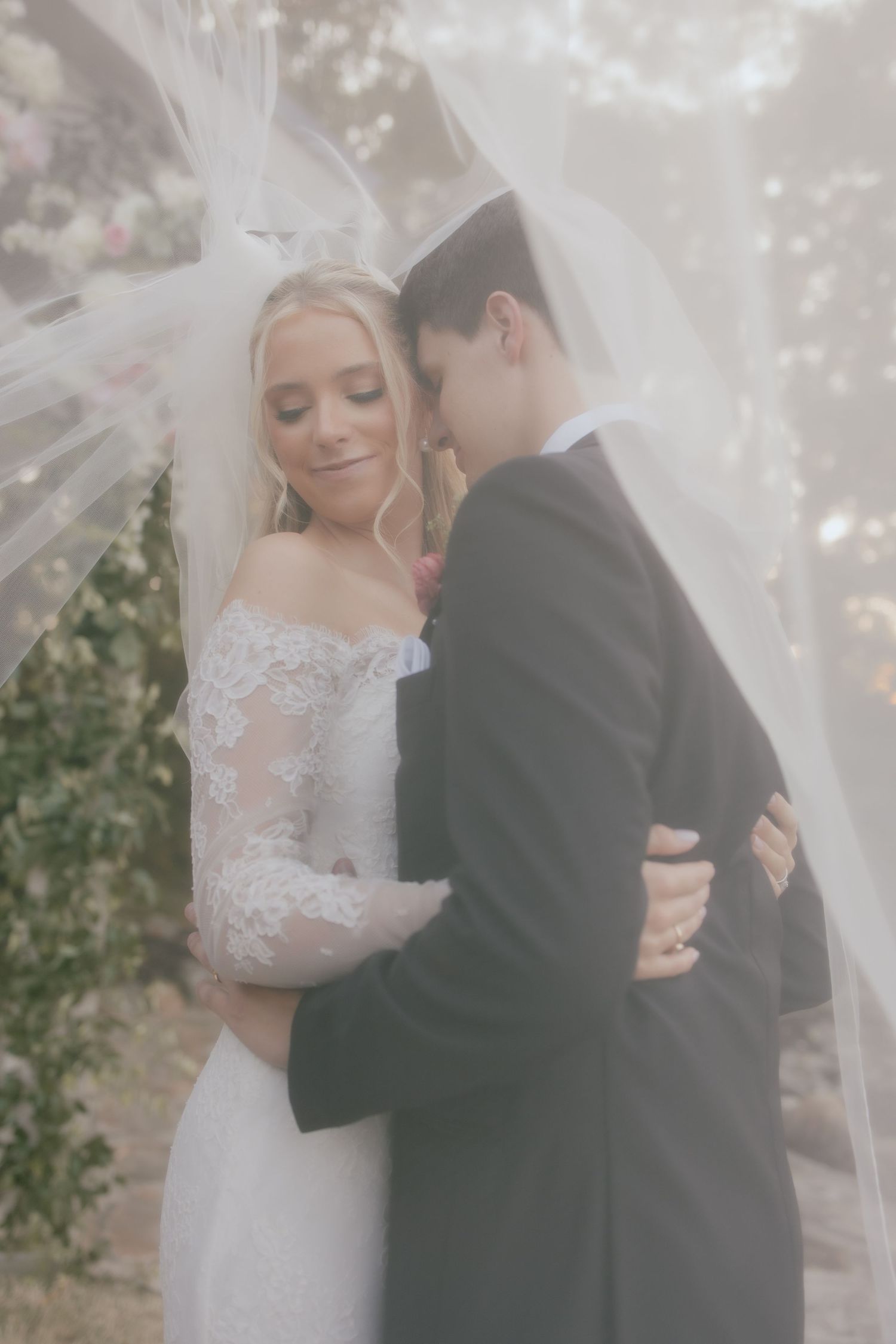Bride and groom under veil at their classic wedding in Arkansas during a romantic moment for their wedding day couples portraits.