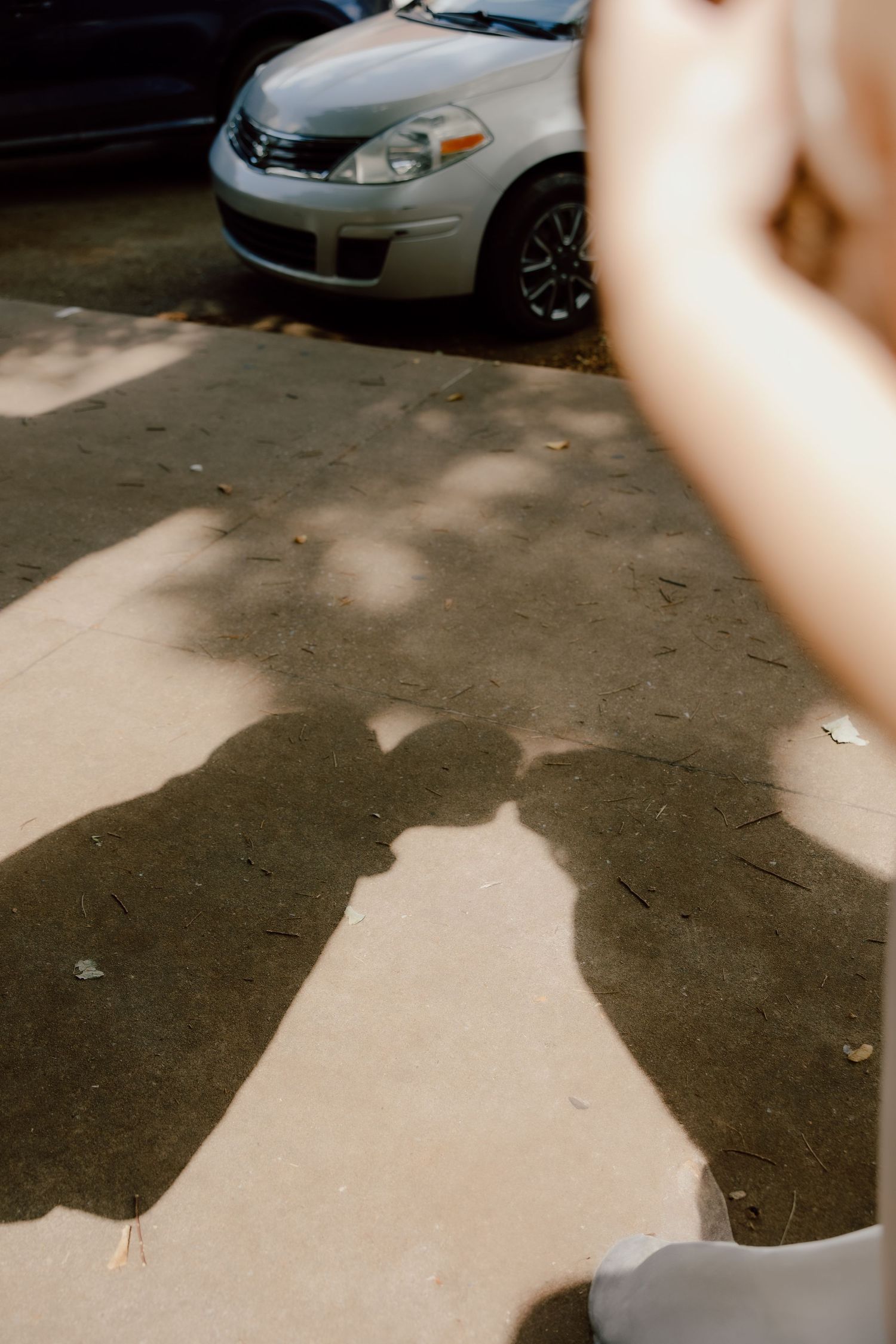 Unique Editorial photo of bride and groom's shadow on the sidewalk while they are kissing.