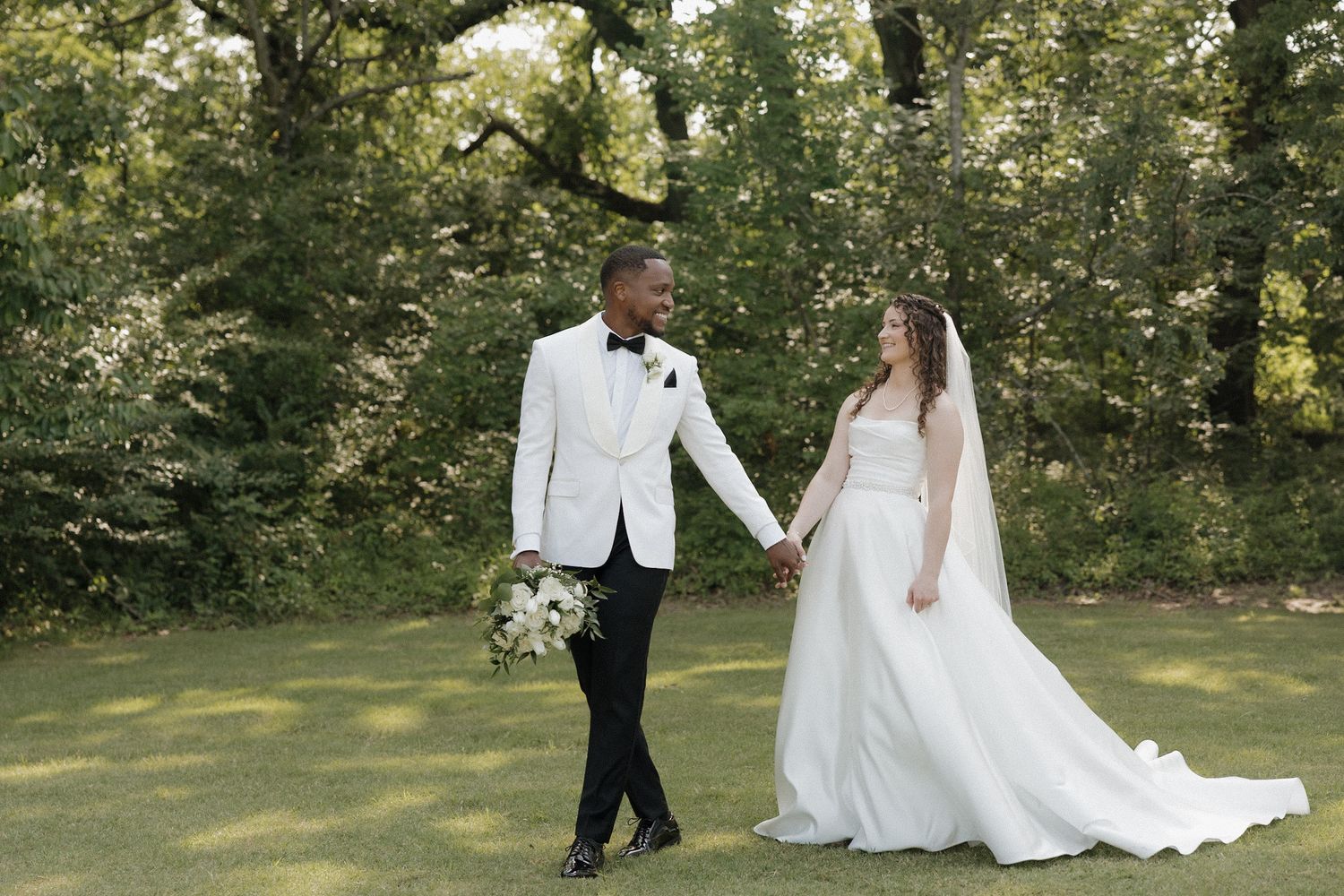 Bride and groom walking along hand in hand outside of their wedding venue during golden hour.