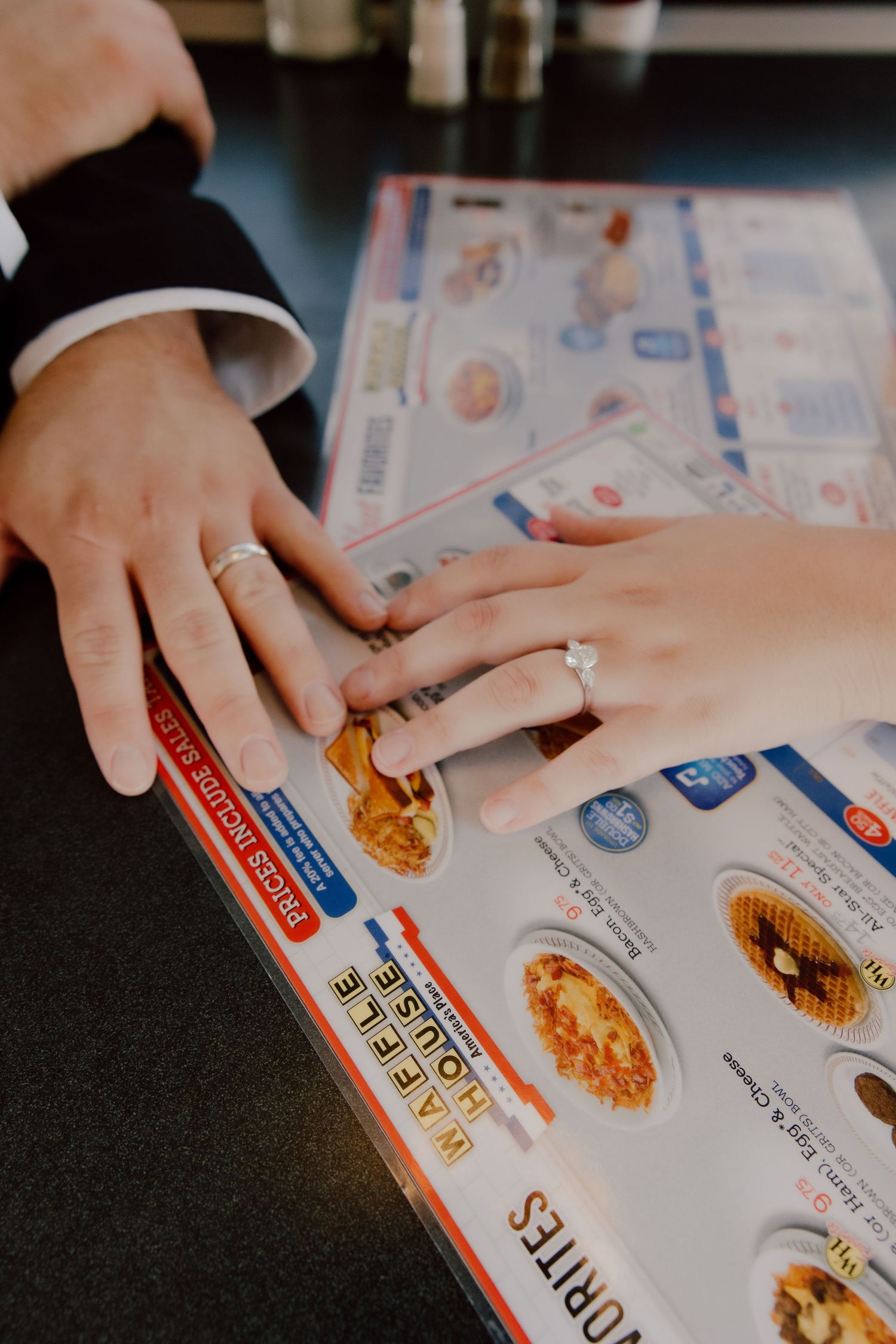 Bride and grooms hands showcasing their wedding rings on top of the Waffle House menu before celebrating their marriage with a unique meal.