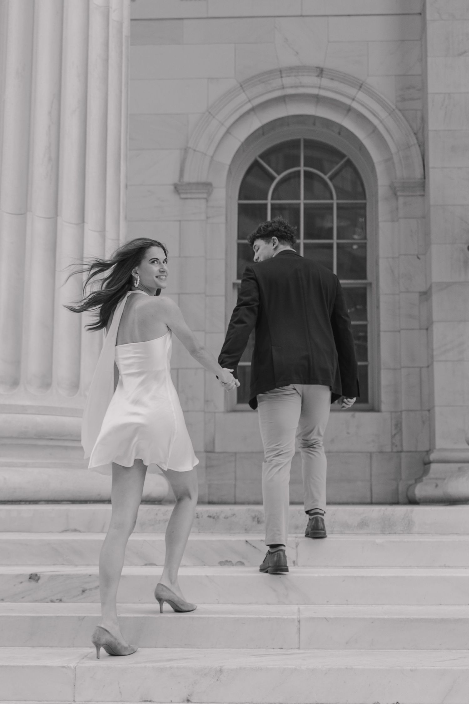 Couple running up the steps at Byron White Courthouse during spring engagement session in downtown Denver