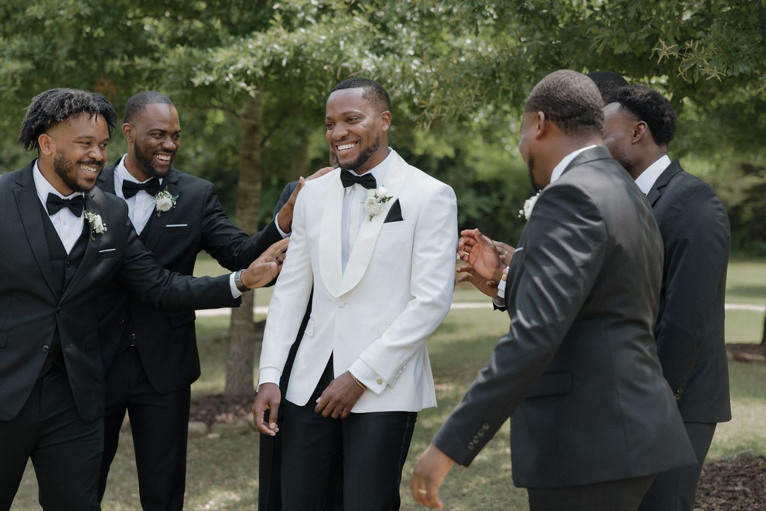 Outside of the Loft at Stone Oak wedding venue, the groomsmen and groom laugh together before ceremony.