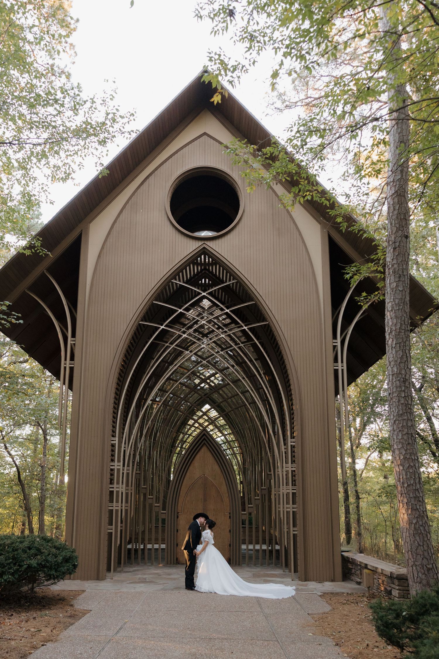 View of bride and groom outside of the Mildred B. Cooper Glass Chapel in Bella Vista, Arkansas