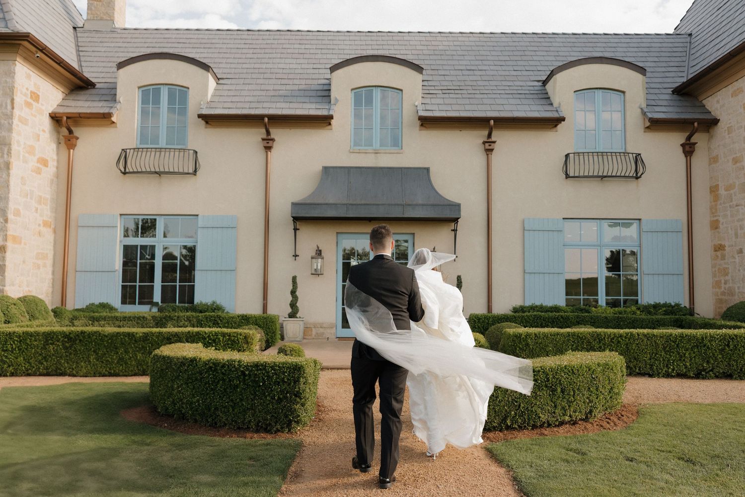 Bride and groom walk into The Bower in Edmond on a windy day.