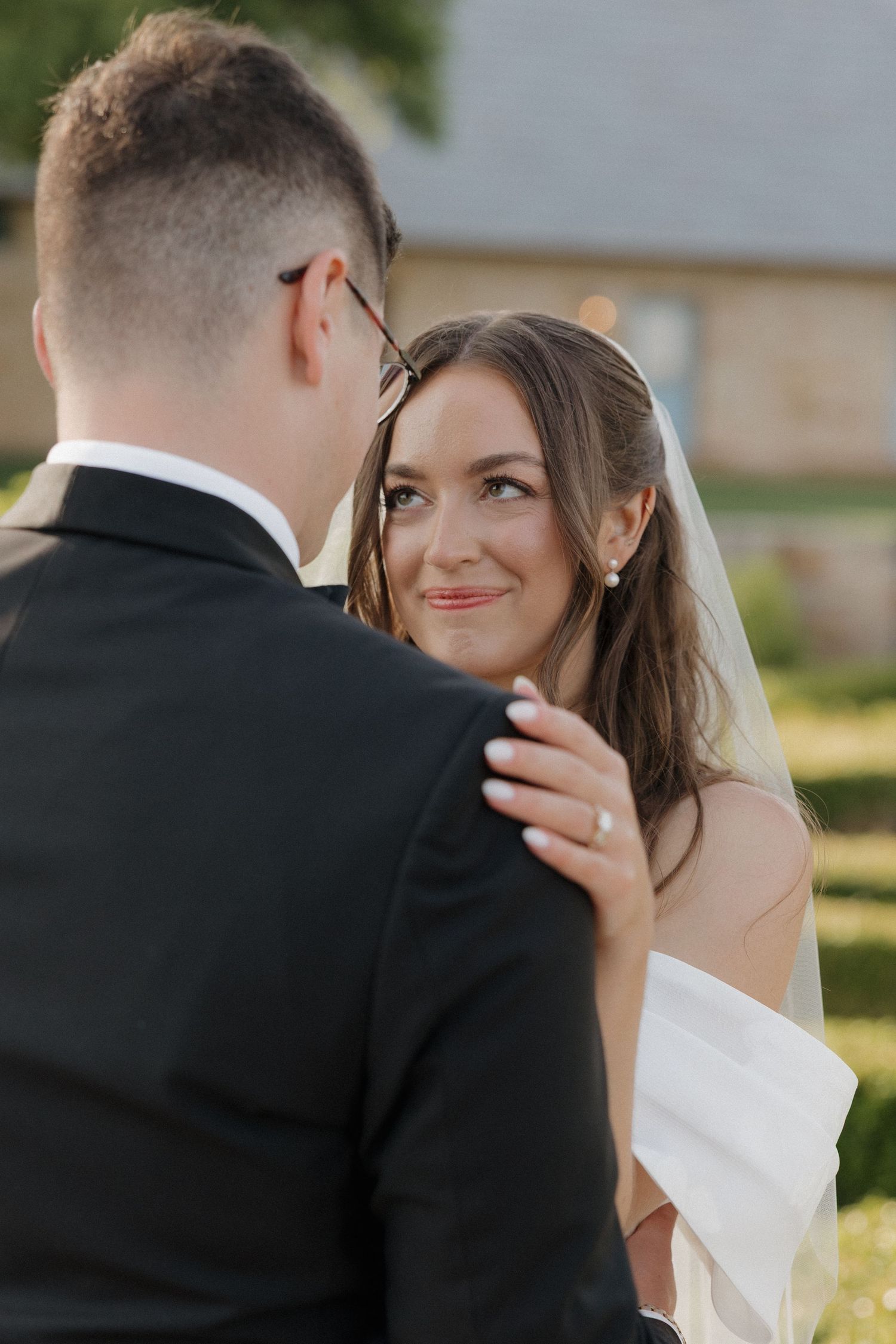 Bride is looking up lovingly at the groom while enjoying the gardens of The Bower during sunset golden hour portraits.