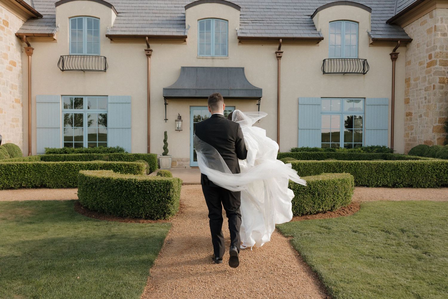 Documentary style photo of bride and groom walking into The Bower on a windy day.
