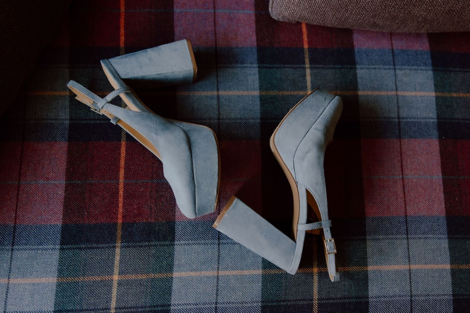 Brides blue wedding shoes on the plaid couch in an editorial style moment.
