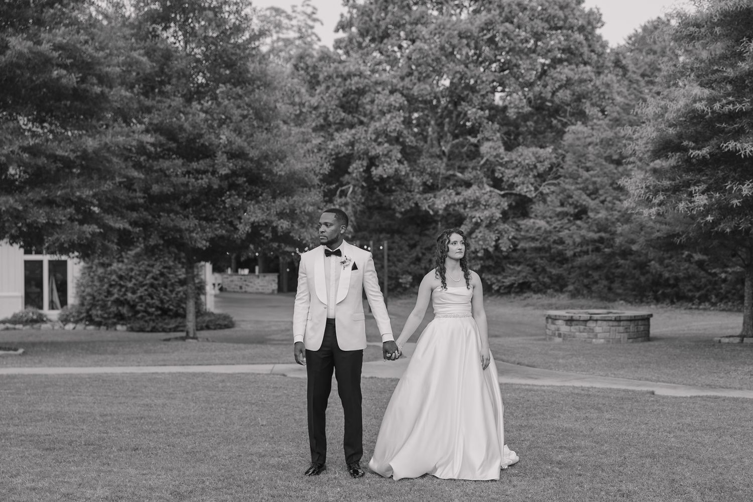 Bride and groom holding hands facing away from one another in front of wedding venue The Loft at Stone Oak.