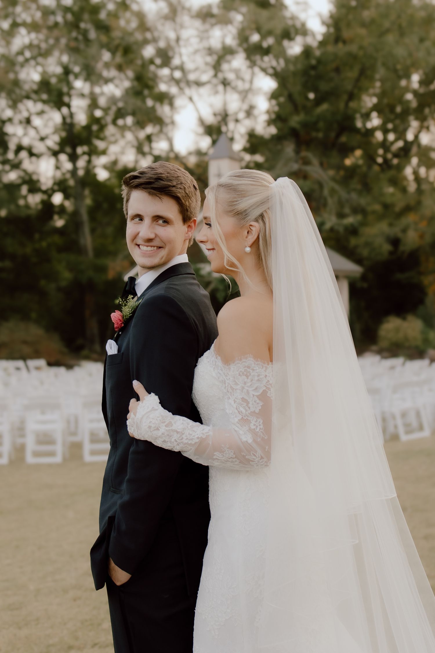 Warm, timeless wedding photo of couple in candid laughing moment at their summer wedding day in Arkansas featuring warm peach and green.