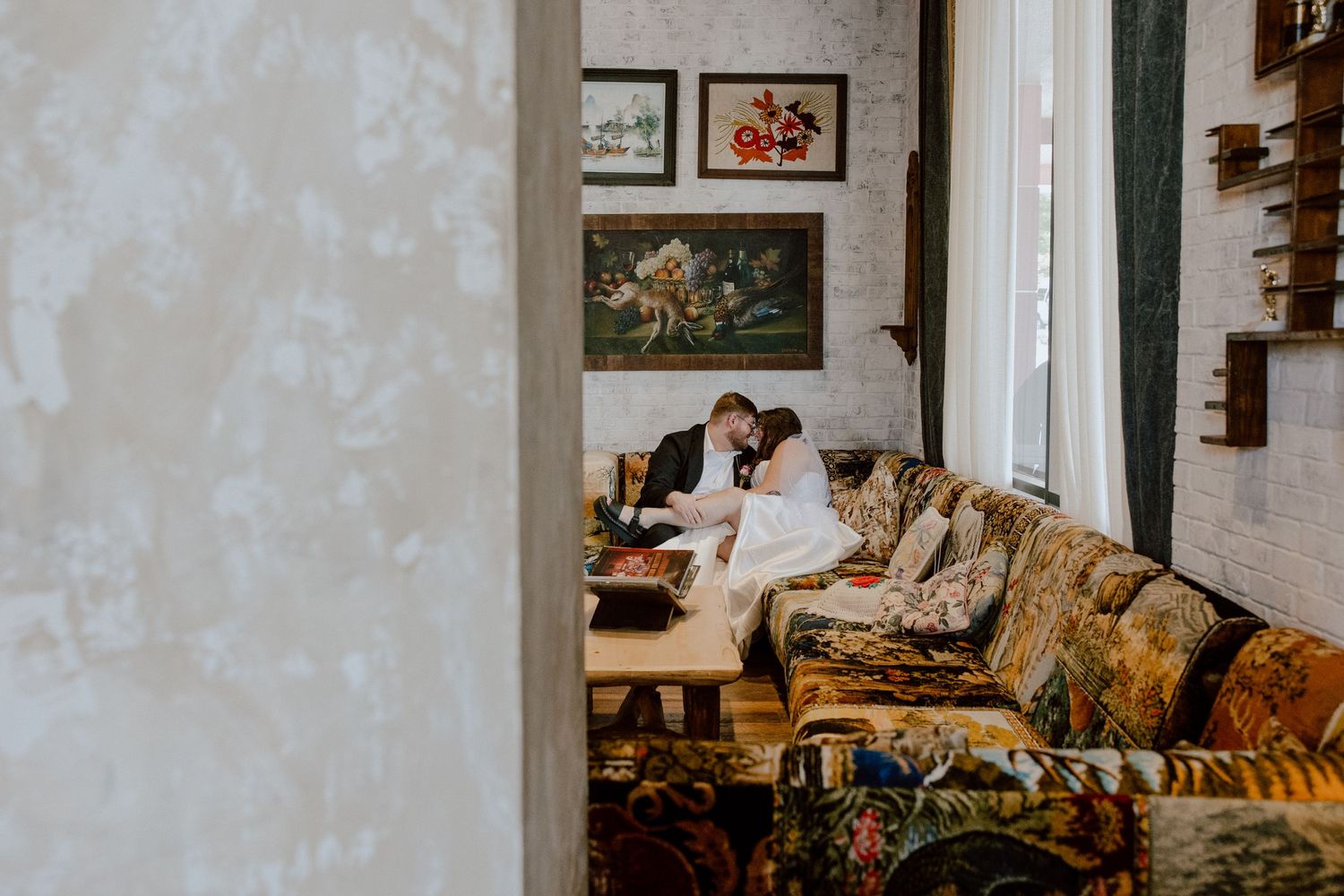 Bride and groom sitting cuddling on funky eclectic couch at this one of a kind wedding venue in Arkansas.