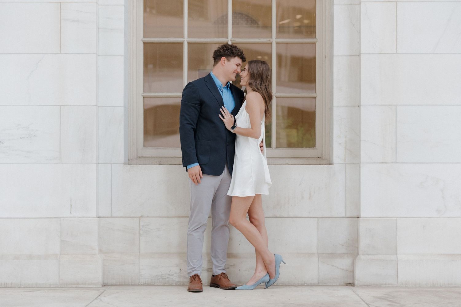 Editorial engagement photo with movement outside Byron White Courthouse, bride in short white dress and groom in gray slacks