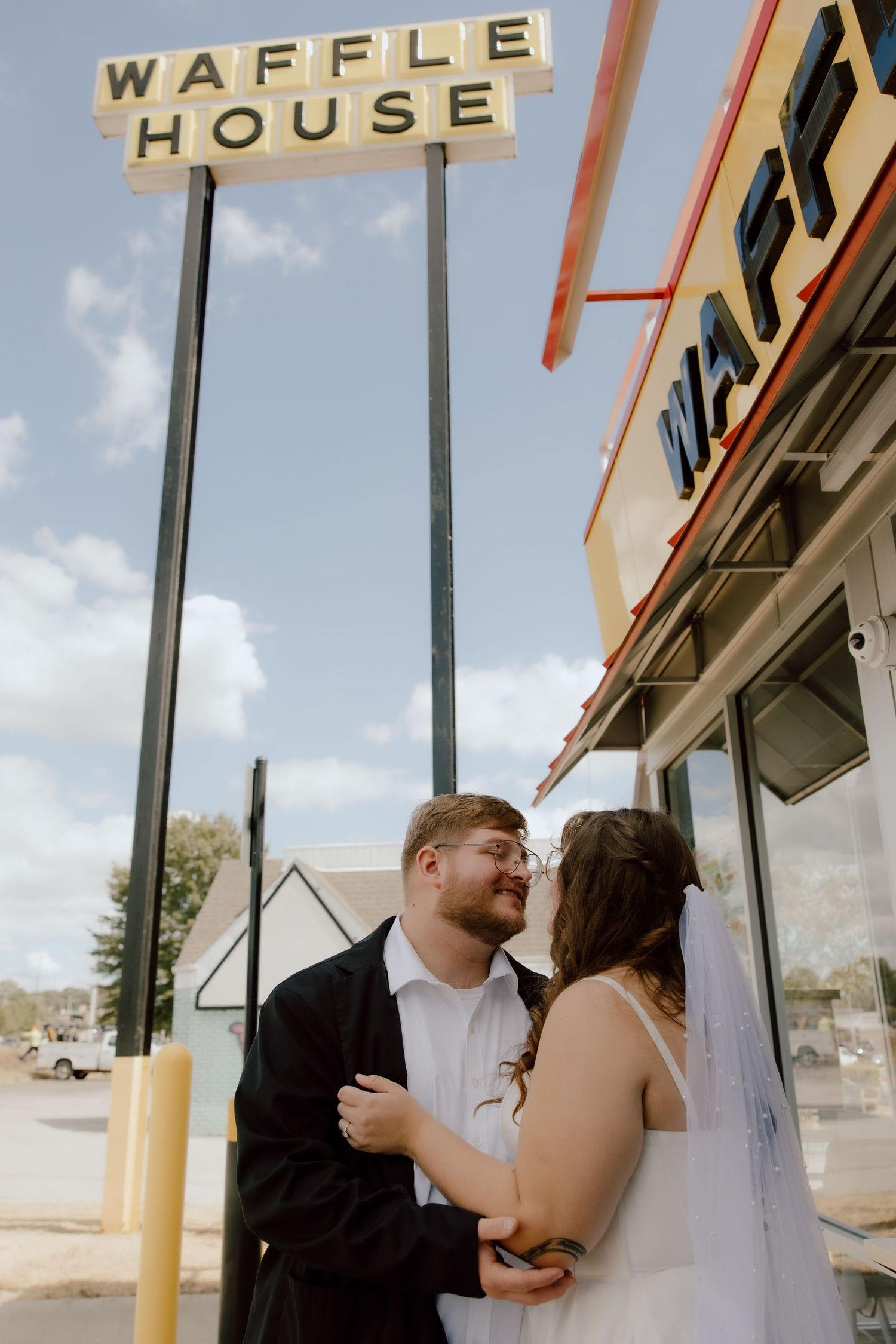 Bride and groom looking at each other in a sweet moment documented in front of the Waffle House sign in NWA on their wedding day.