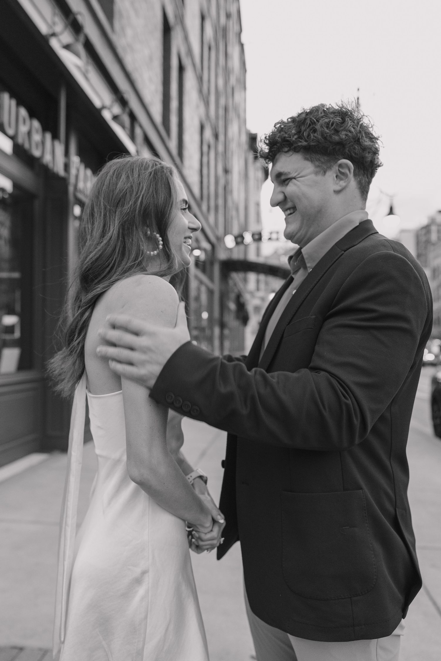 Couple hugging and smiling near the train platform at Union Station during a downtown Denver engagement shoot