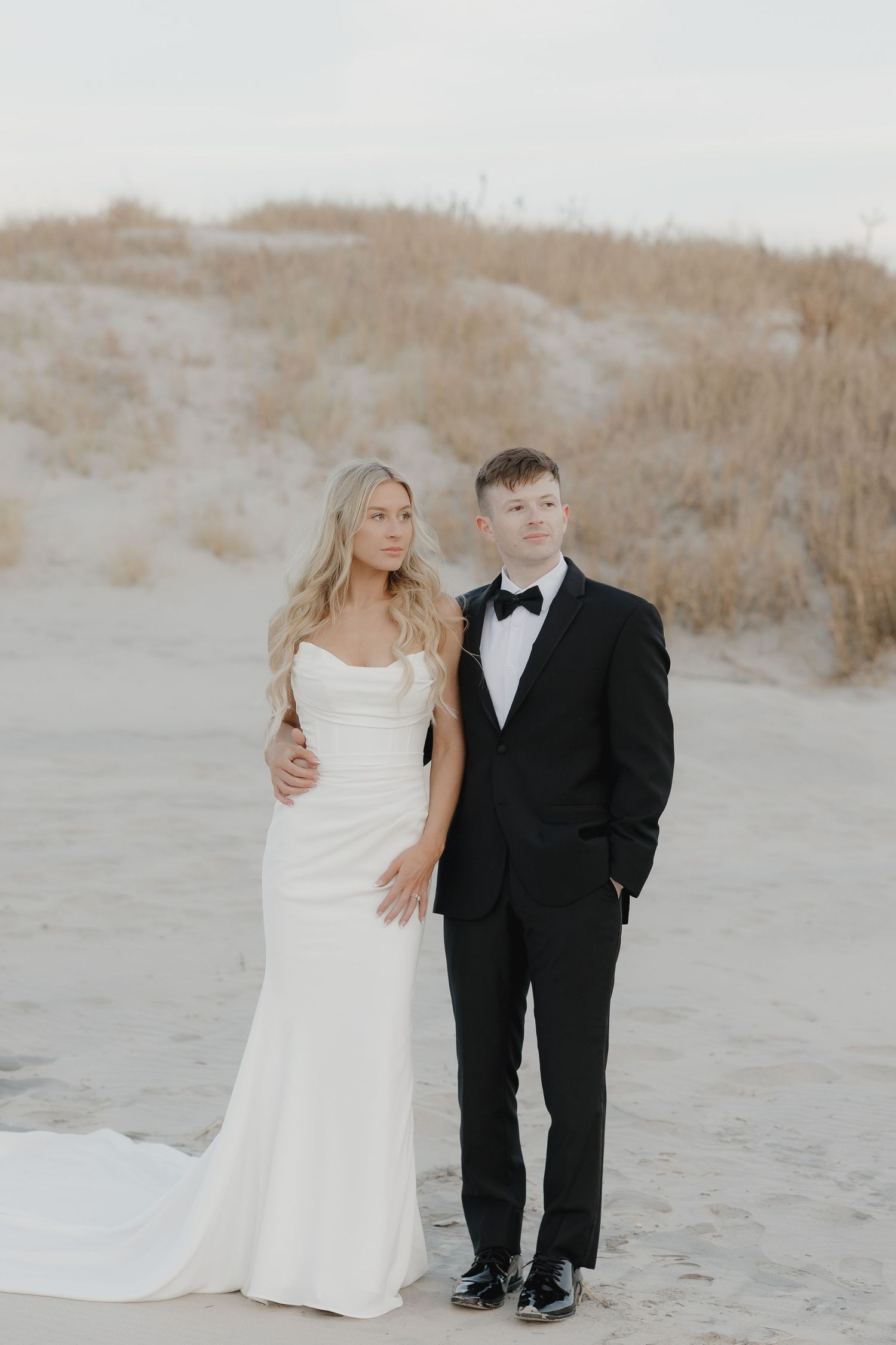 Bride and groom posing together on a New Jersey beach after their wedding ceremony.