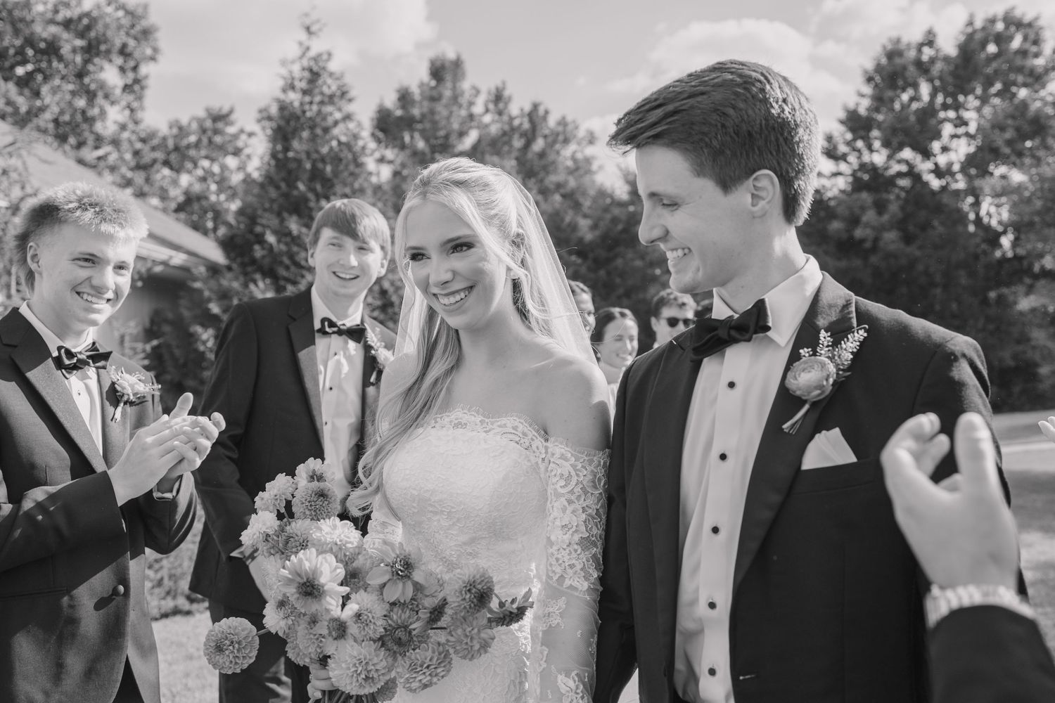 Bride and groom happy and smiling on their wedding day surrounded by wedding party.