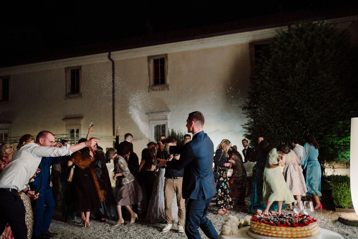 Night time wedding reception with guests dancing under outdoor lighting.