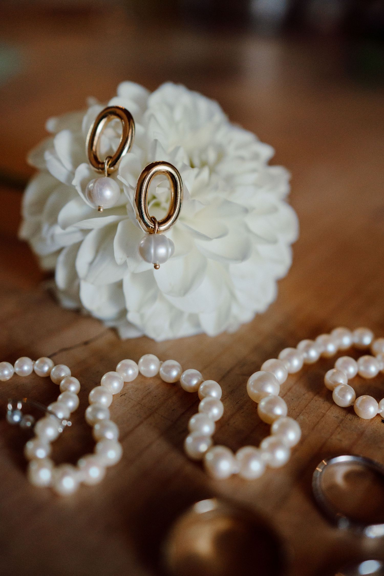 Dettaglio fotografico con composizione di orecchini, collana sposa e fiore