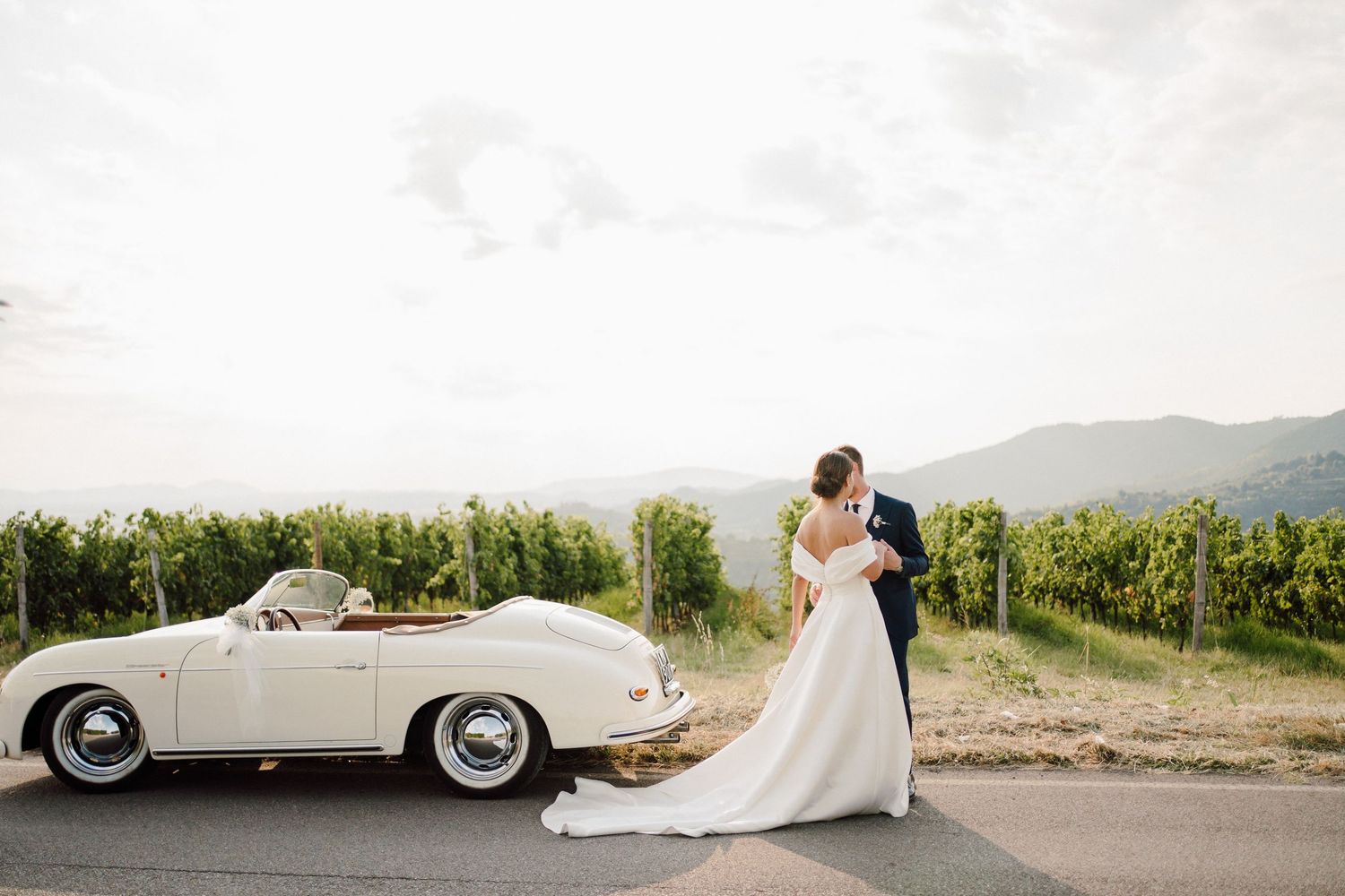 fotografia di ritratto sposi con auto d'epoca porche bianca in mezzo alle vigne della franciacorta location Carlomagno Brescia