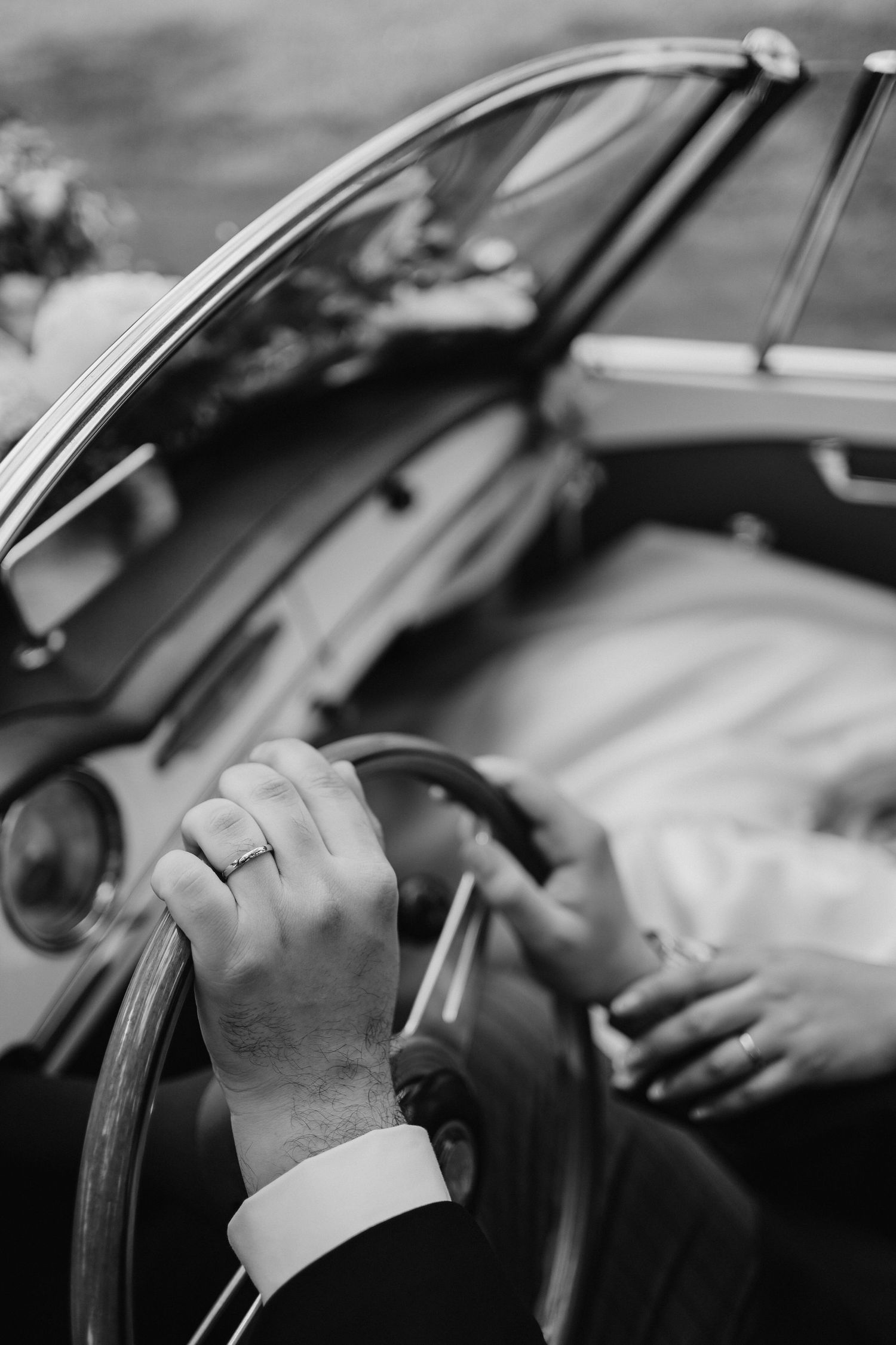 Black and white close-up shots of hands on a car steering wheel.