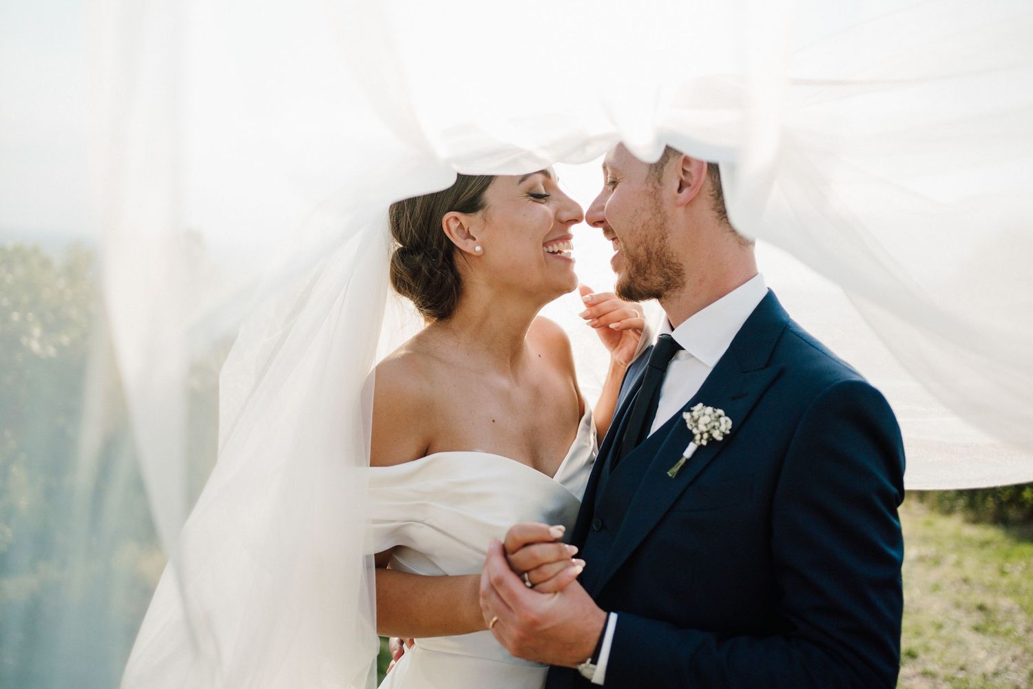 Intimate wedding moment captured against a bright, ethereal background.