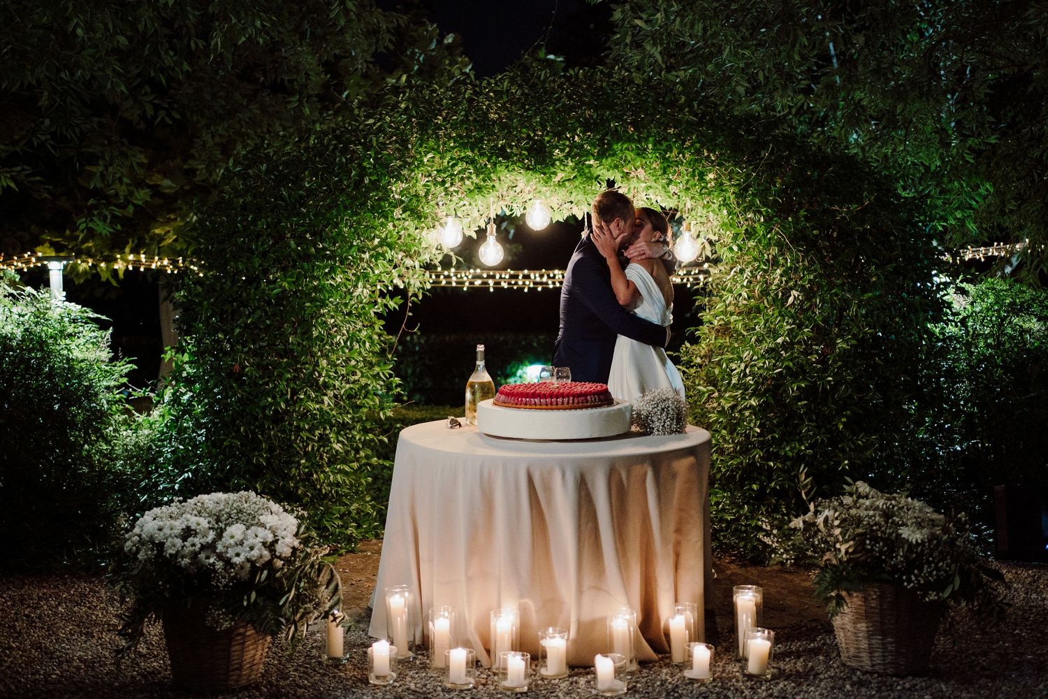 Bacio sposi al taglio torta con luci soffuse e candele, un' atmosfera romantica