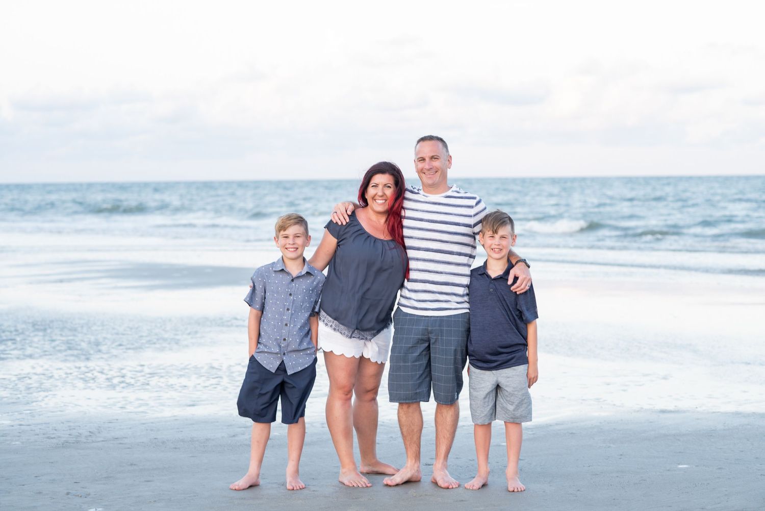 Family group walking along beach shoreline in coordinated blue and white outfits. St. Augustine, family portrait.