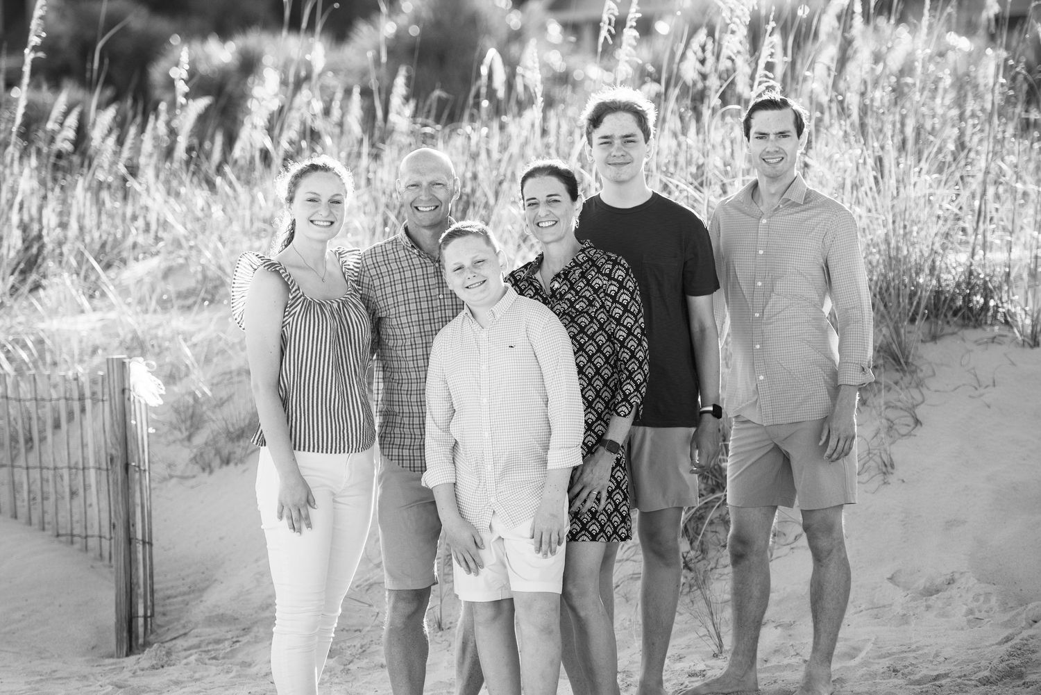 Black and white coastal portrait of group standing together by beach dunes.