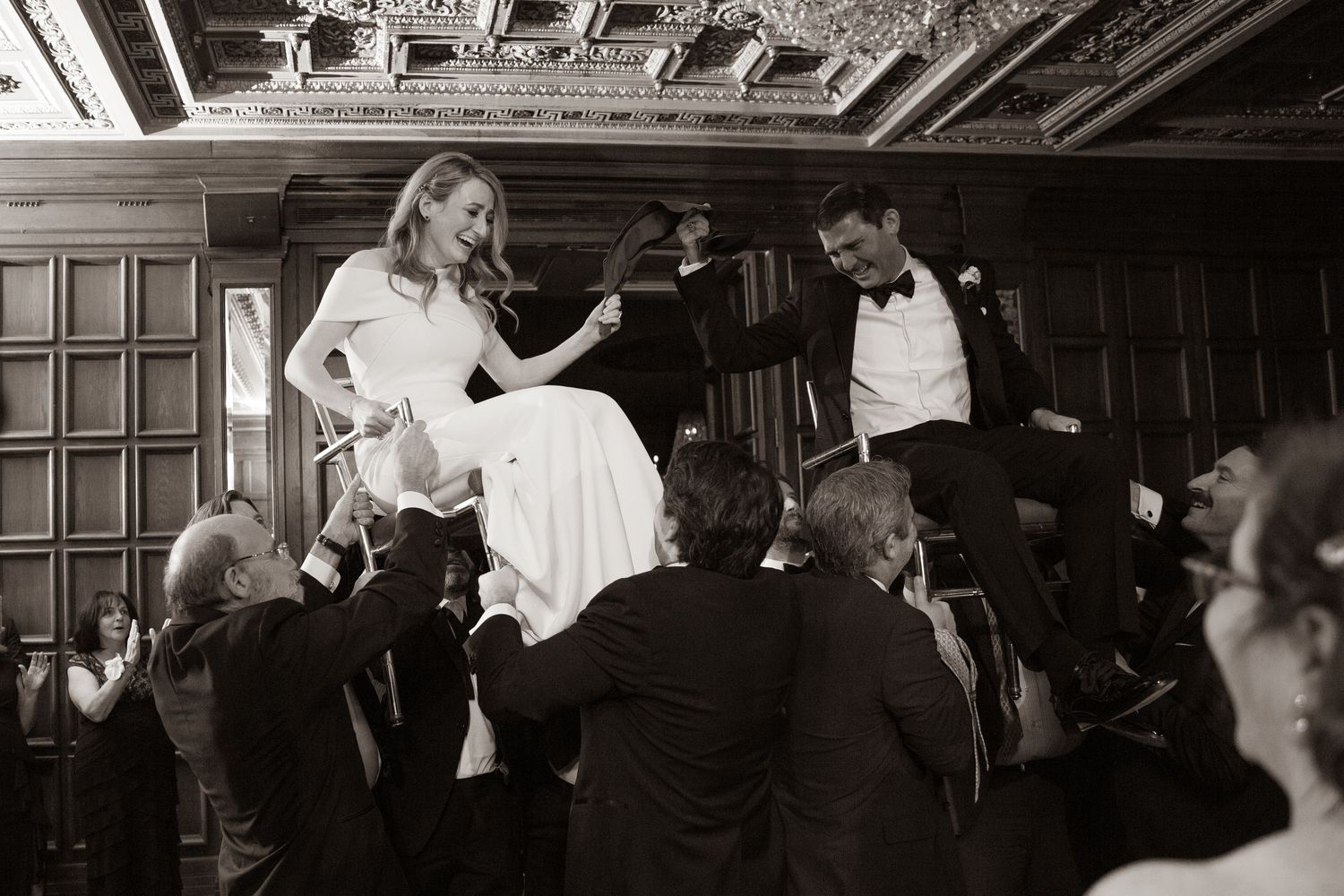 Black and white photo of a couple dancing in an ornate ballroom with decorative wood paneling.