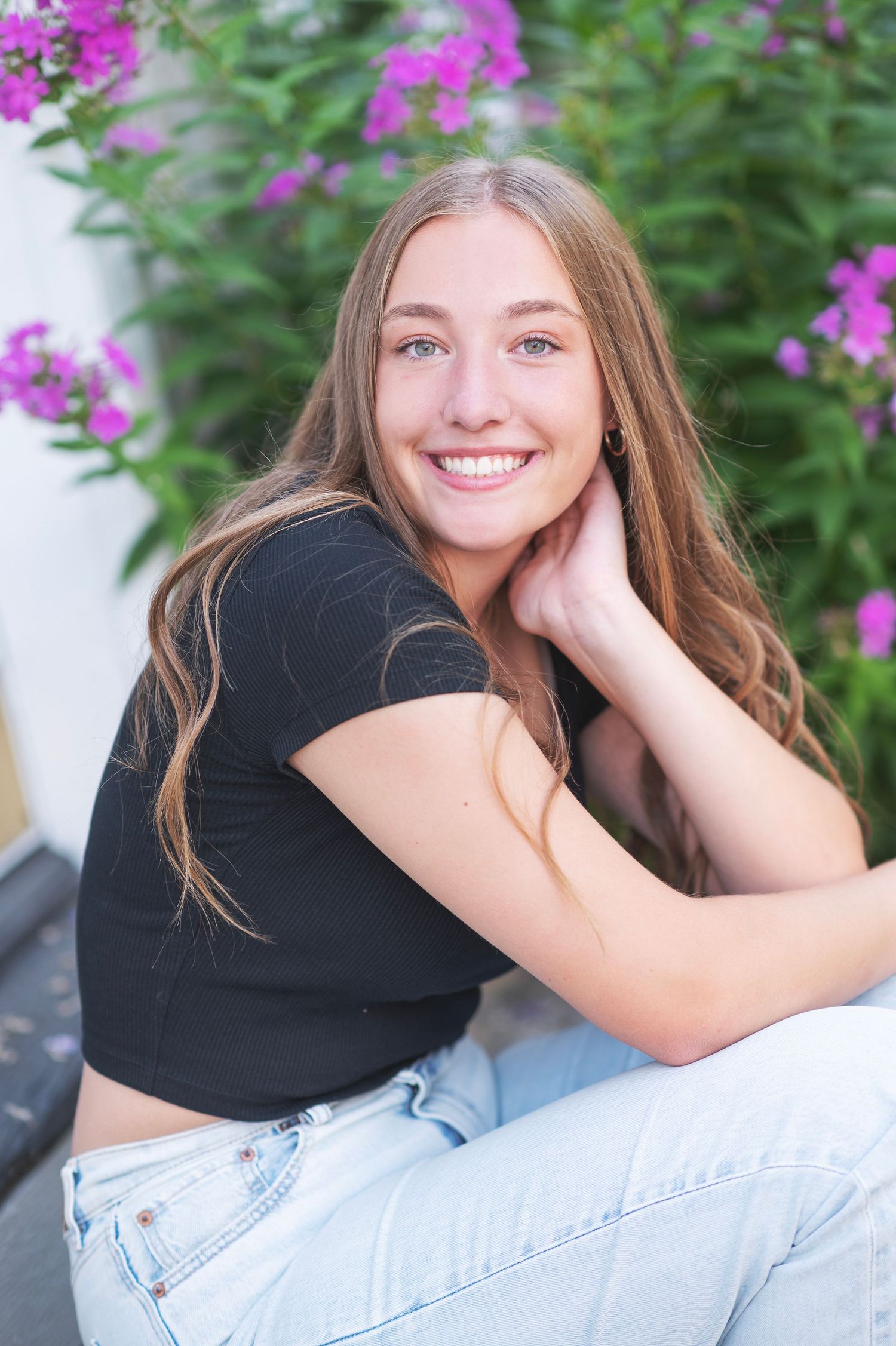 Senior portrait session featuring casual poses with pink flowers in background.