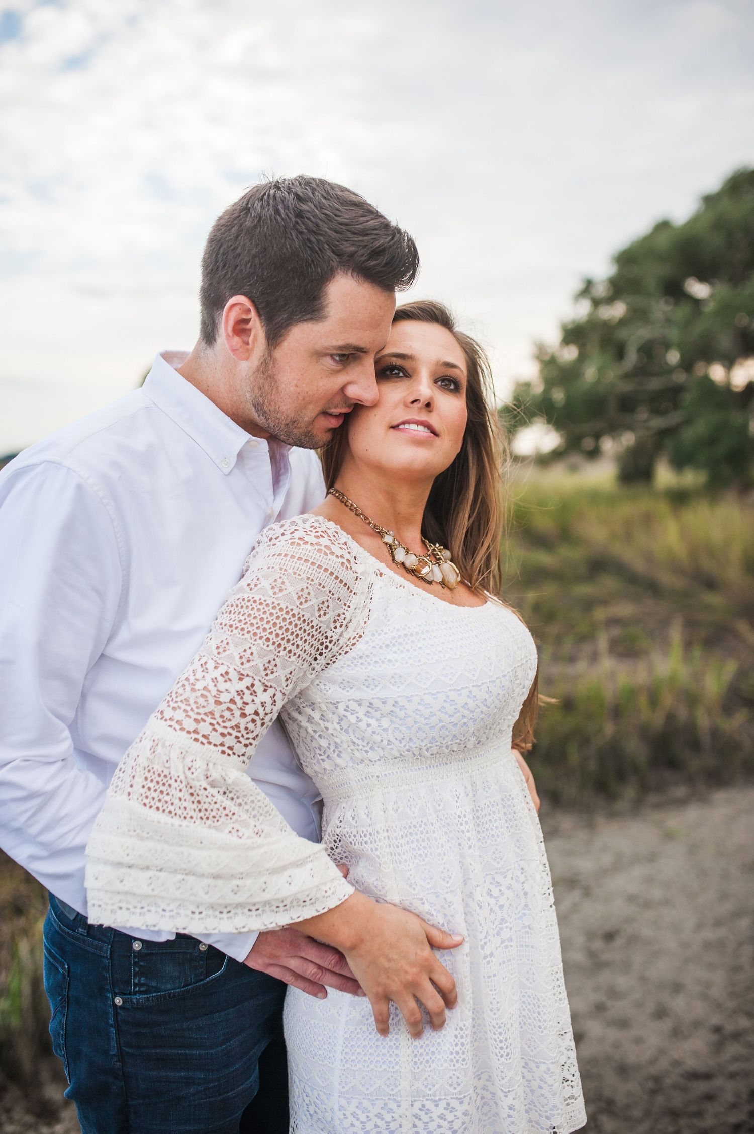 Couple in white and denim share affectionate poses against coastal marsh backdrop. Palmetto Bluff