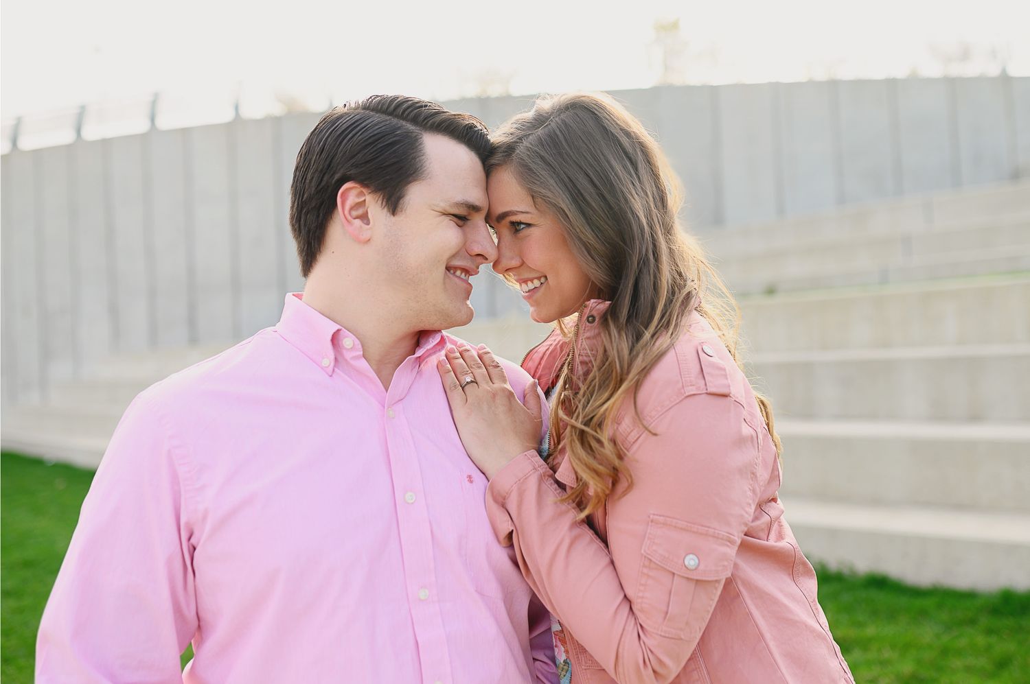 Couple in coordinating pink outfits share a romantic moment outdoors.