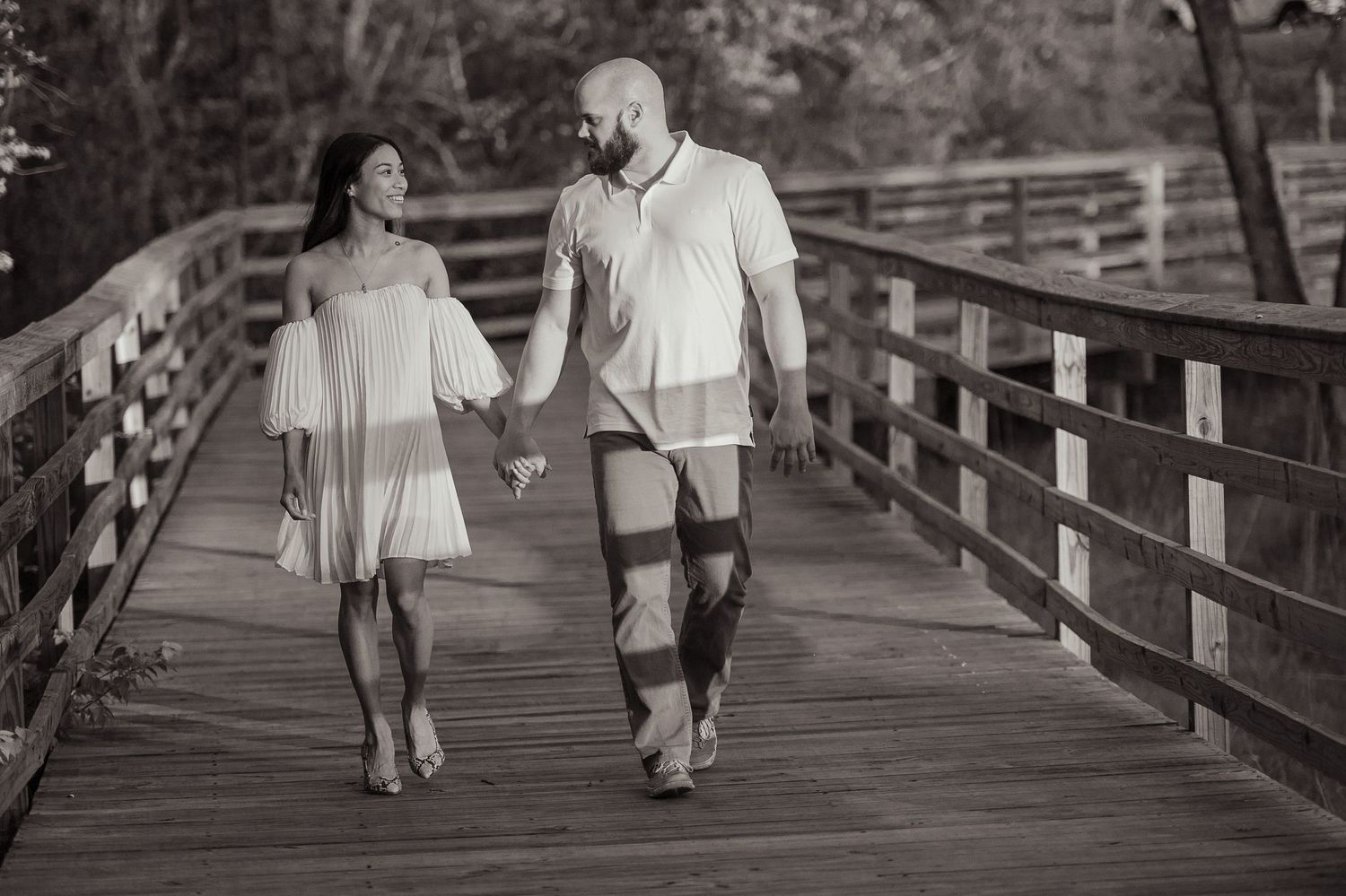 Black and white romantic portrait of couple walking on wooden bridge. Palm Coast, St. Augustine engagement photographer.