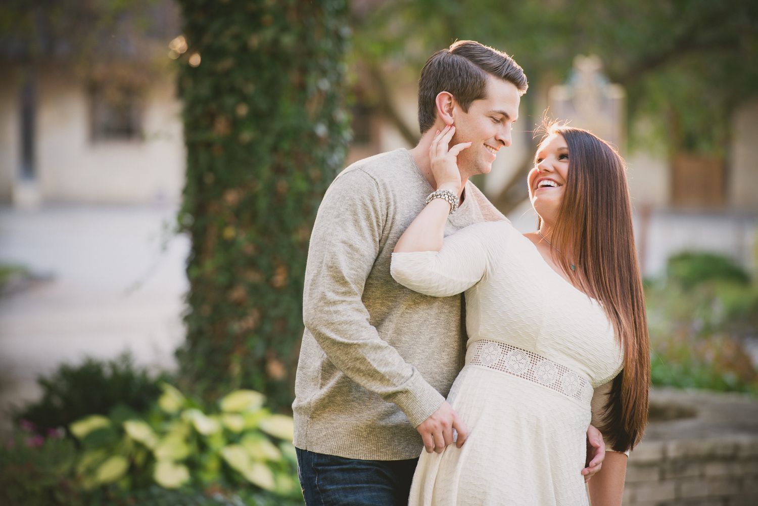Couple in coordinating outfits shares tender moment in garden setting.