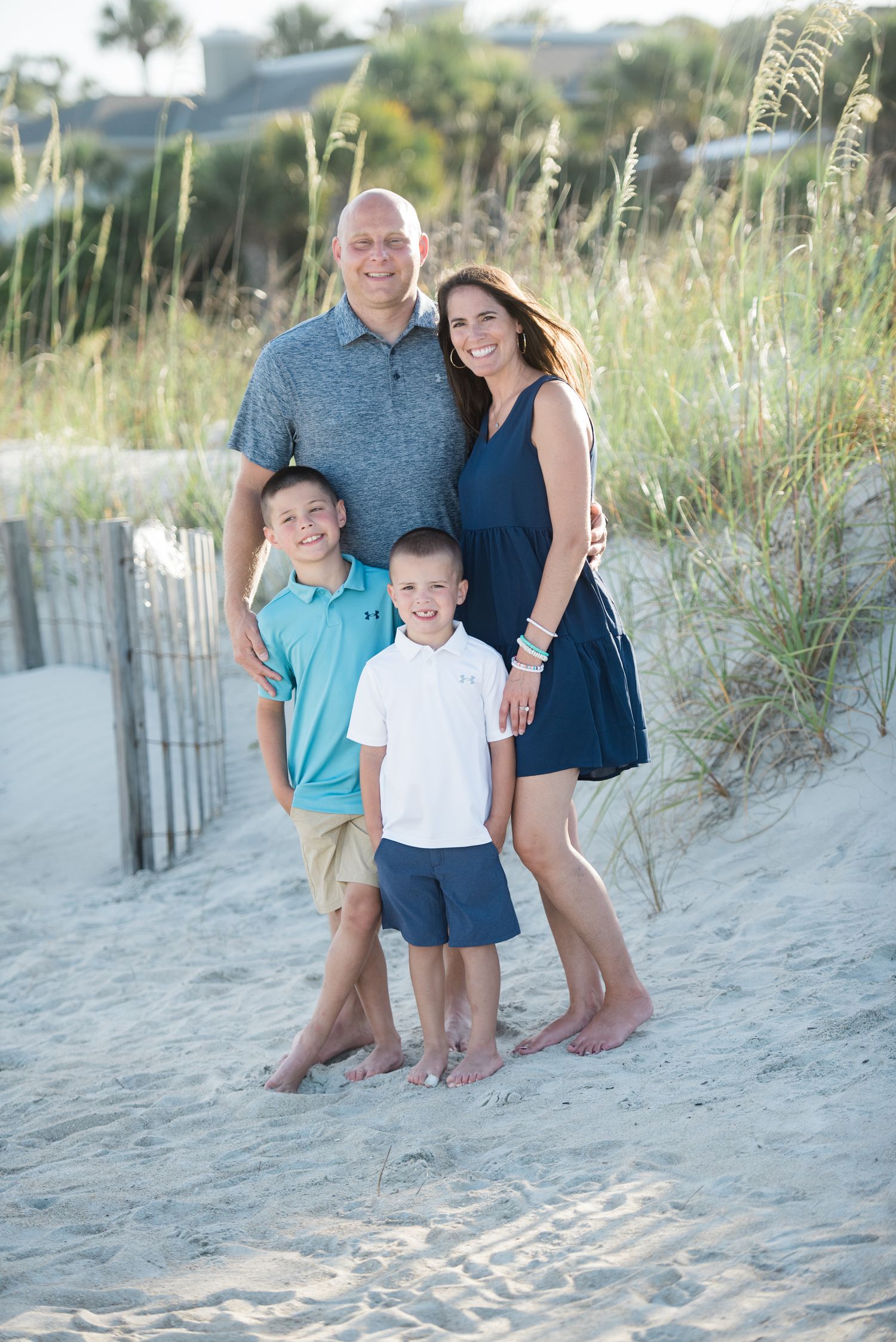 Family enjoying a casual beach photoshoot together among sand dunes and beach grass at sunset.Hammock Beach, Sea Pines coastal photography.
