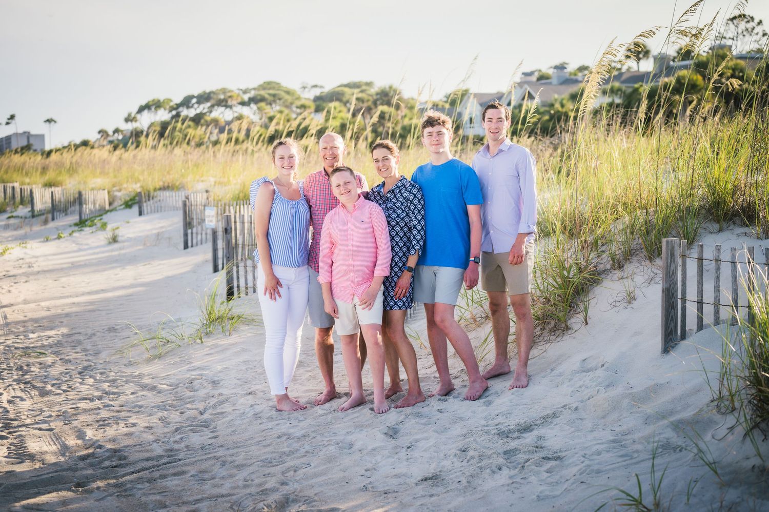 Beach portrait session with family members in coordinating pastels against coastal landscape.Hammock Beach, Sea Pines coastal photography.