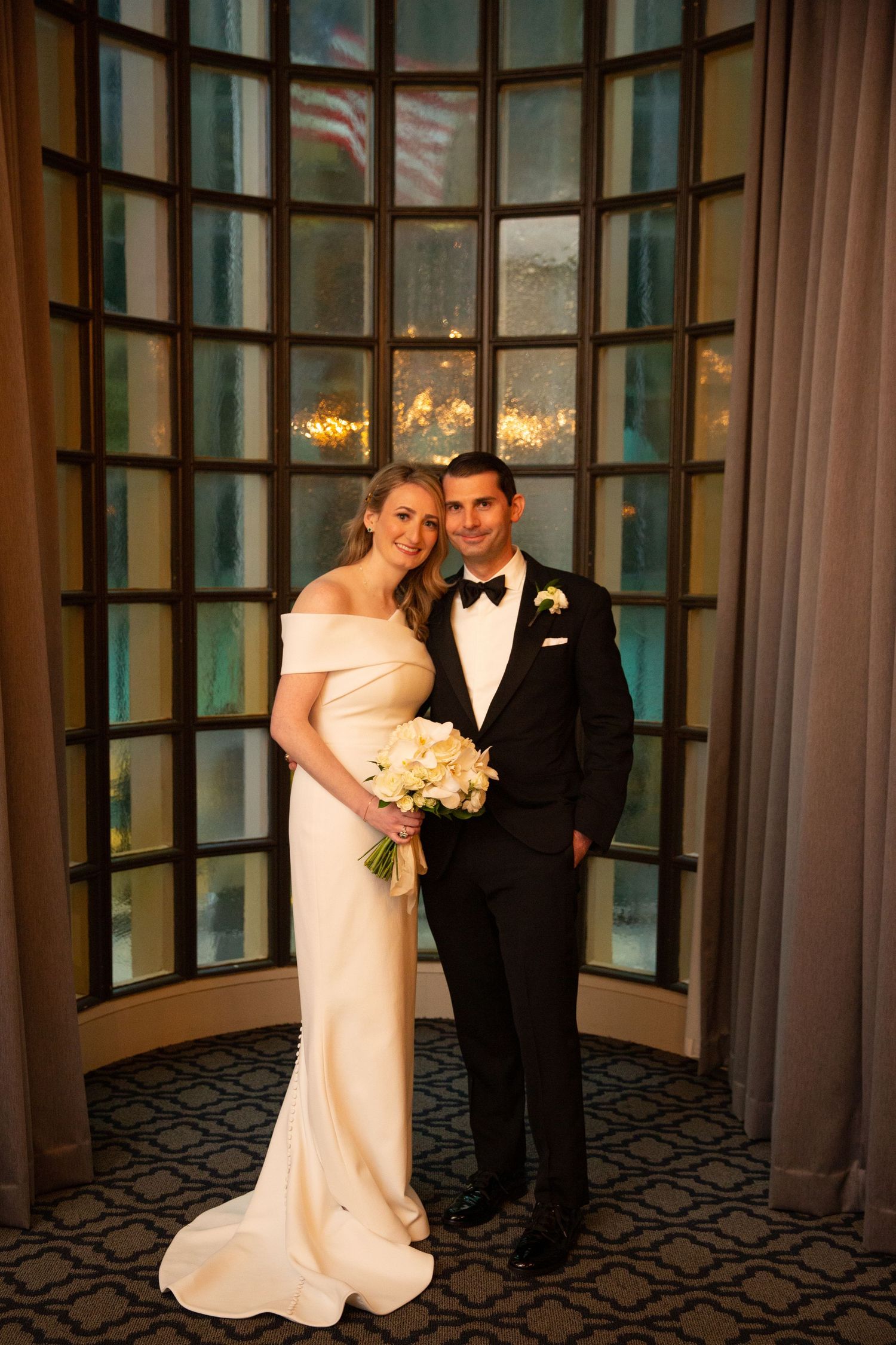 Romantic wedding portraits in an elegant room with curved windows and warm lighting.
