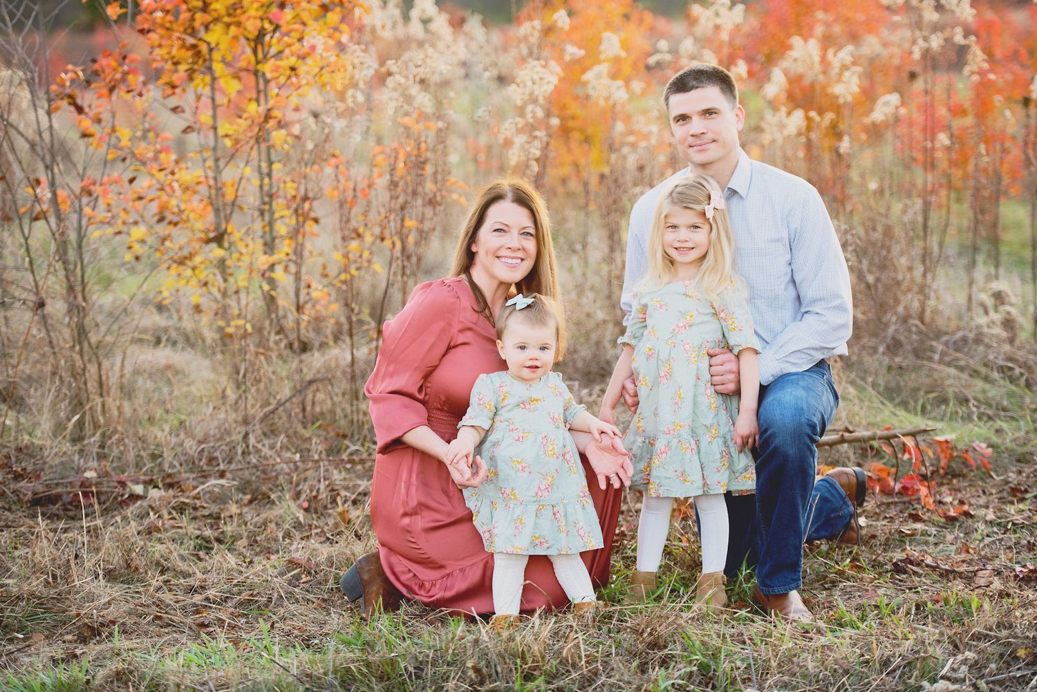 Family portrait in autumn setting with vibrant orange foliage.